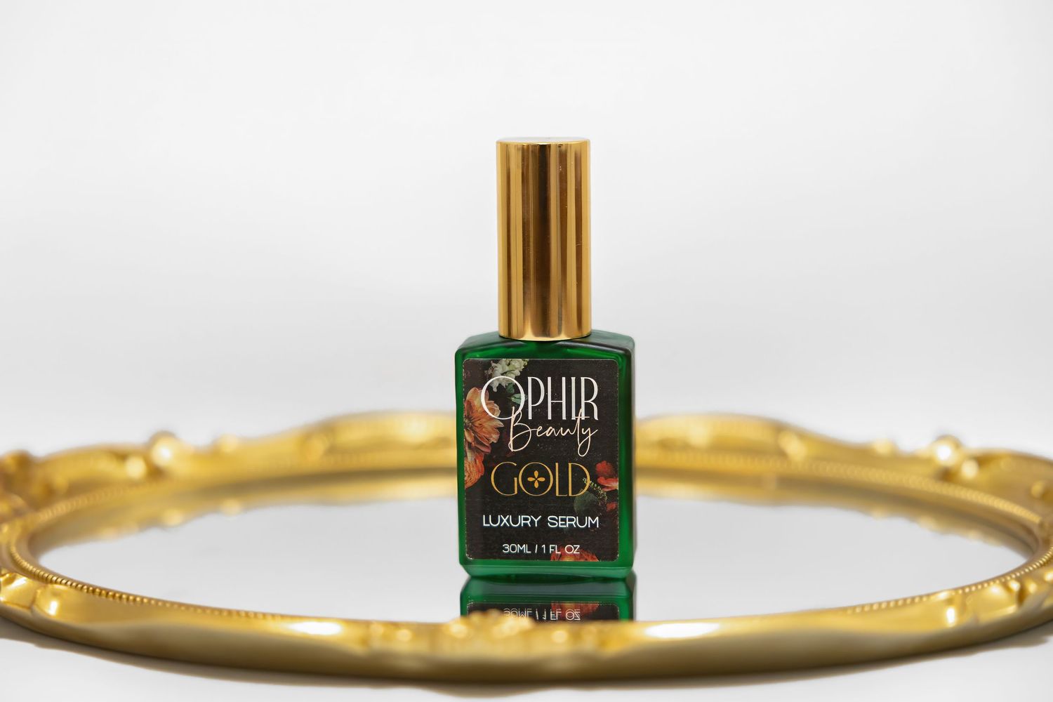 a single bottle of Ophir gold luxury serum sits on a gilded mirror tray with a white background