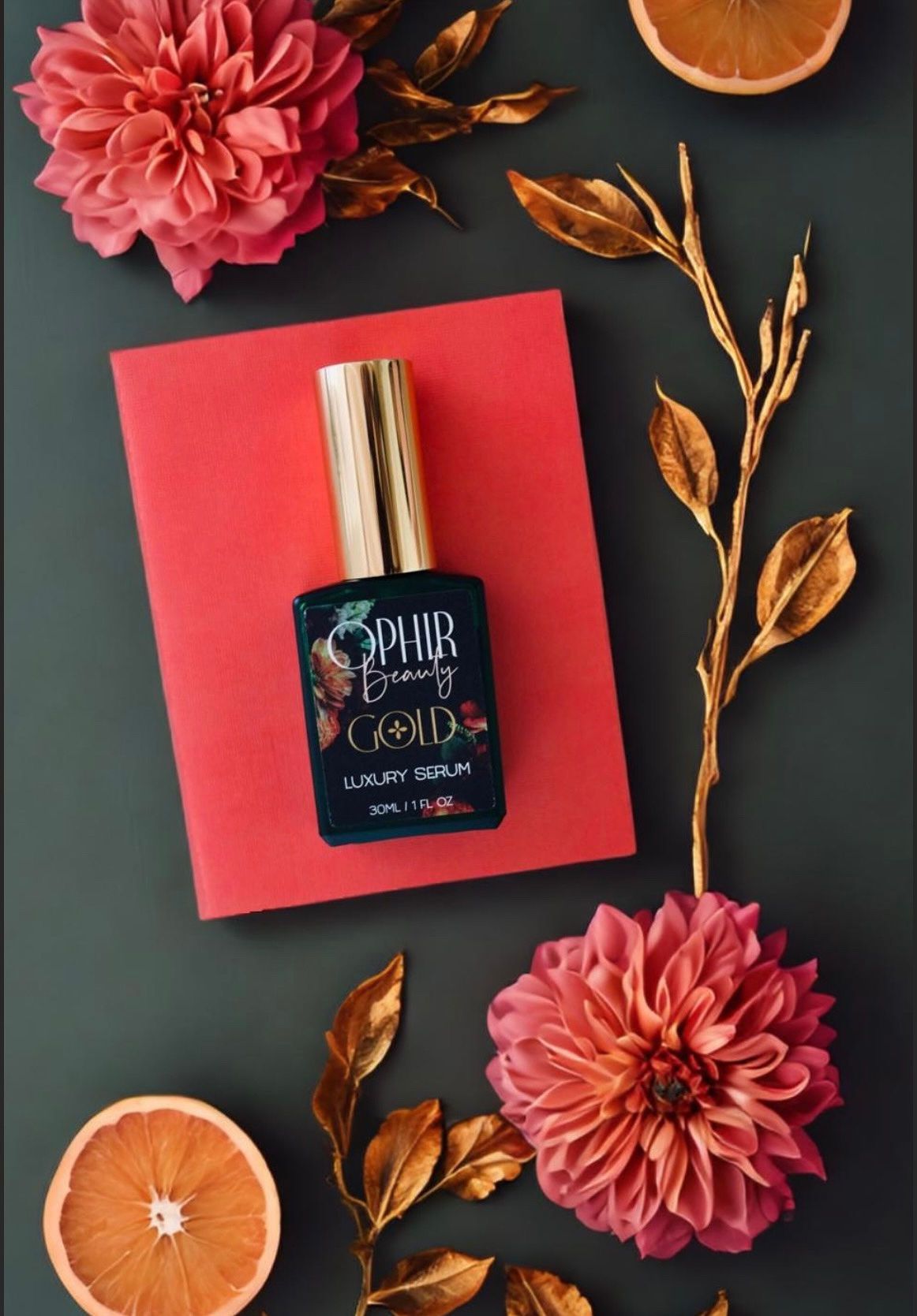 a bottle of ophir gold serum lies on a bright pink envelope, with pink and gold zinnias around