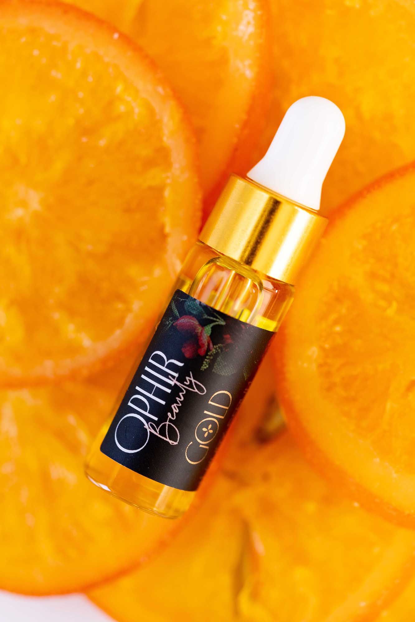 a sample sized Ophir Gold bottle lies on freshly sliced oranges