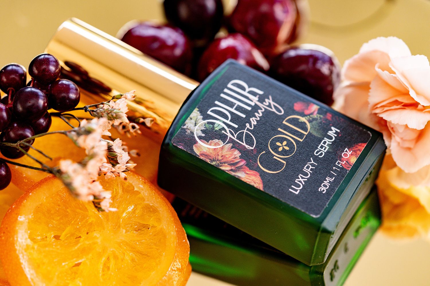 A single bottle of Ophir gold is displayed with fresh fruits and berries