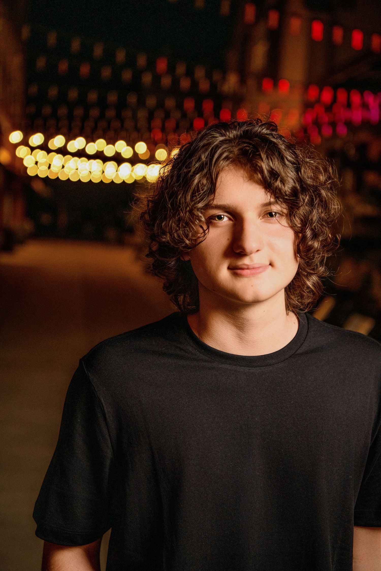 Portrait of person in black t-shirt with bokeh lights in background.