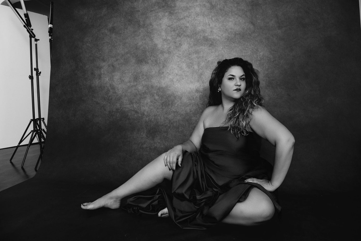 Dramatic black and white studio photo of someone in dark dress reclining.