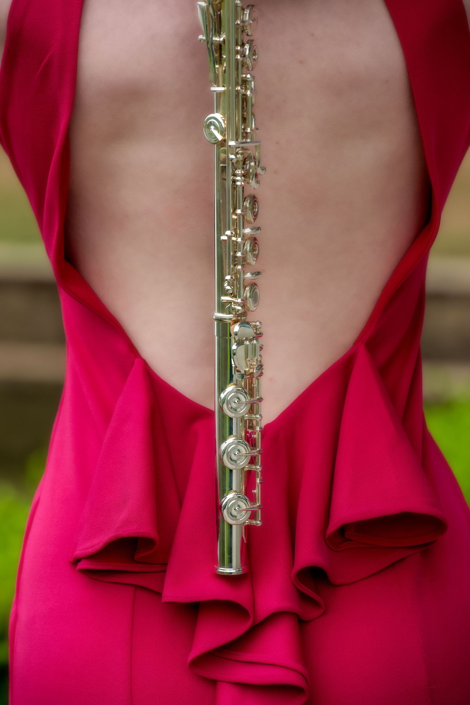 Close-up detail of silver flute against red formal dress with draped back.