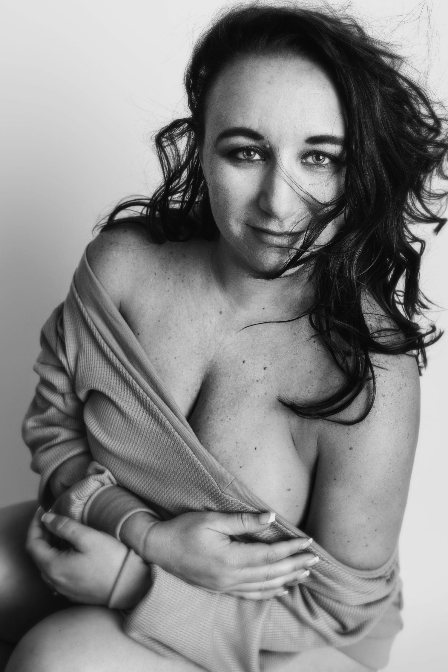 Intimate black and white portrait showing model in soft beige sweater with tousled hair.