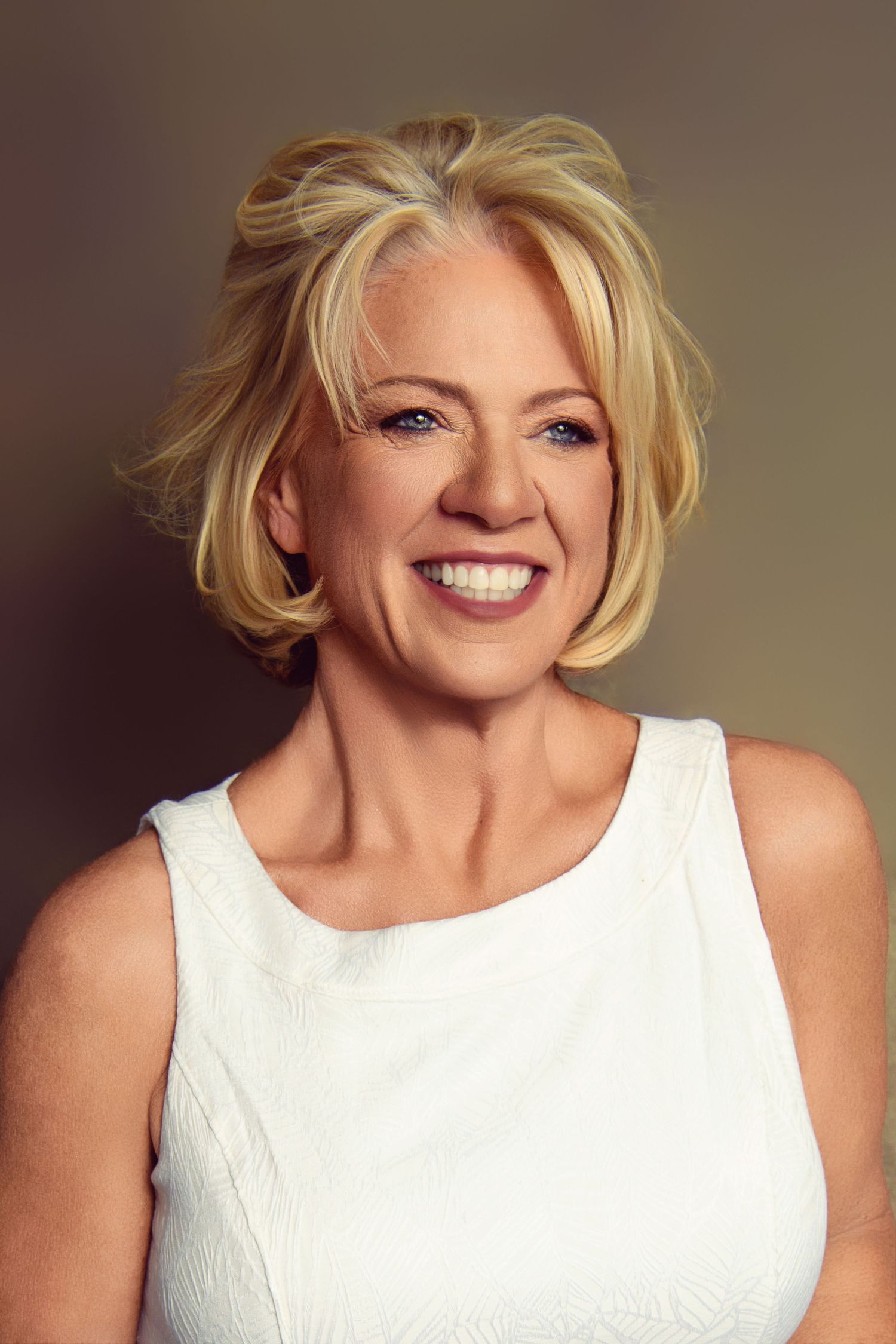 Warm studio portrait with classic white tank top and natural makeup.