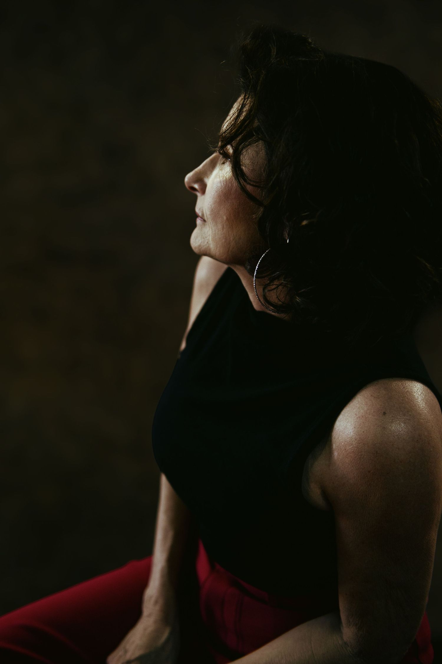 Side profile of person wearing glasses in dramatic low-key lighting.