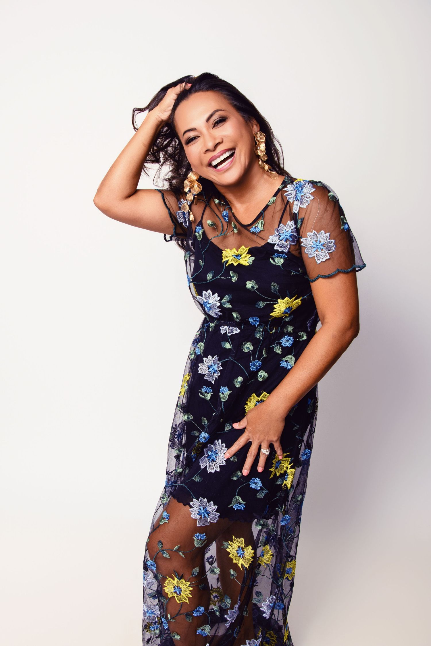 Joyful portrait of someone wearing a navy floral dress with sheer overlay.