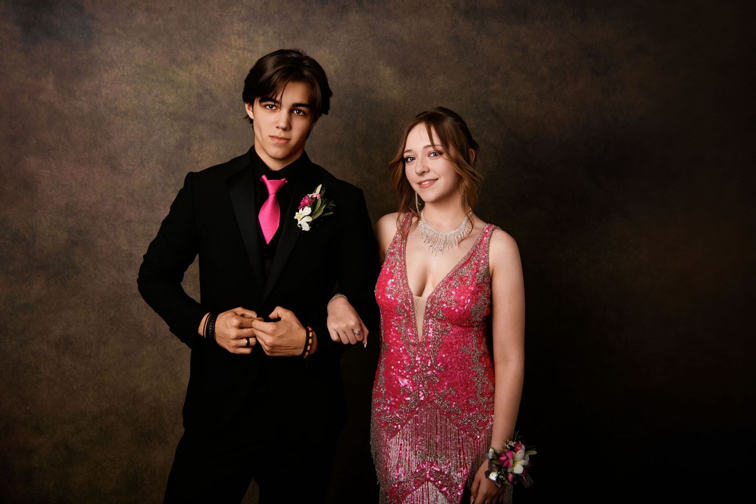 Formal prom photo of a couple, with woman in sparkly pink dress and man in black suit with pink tie.