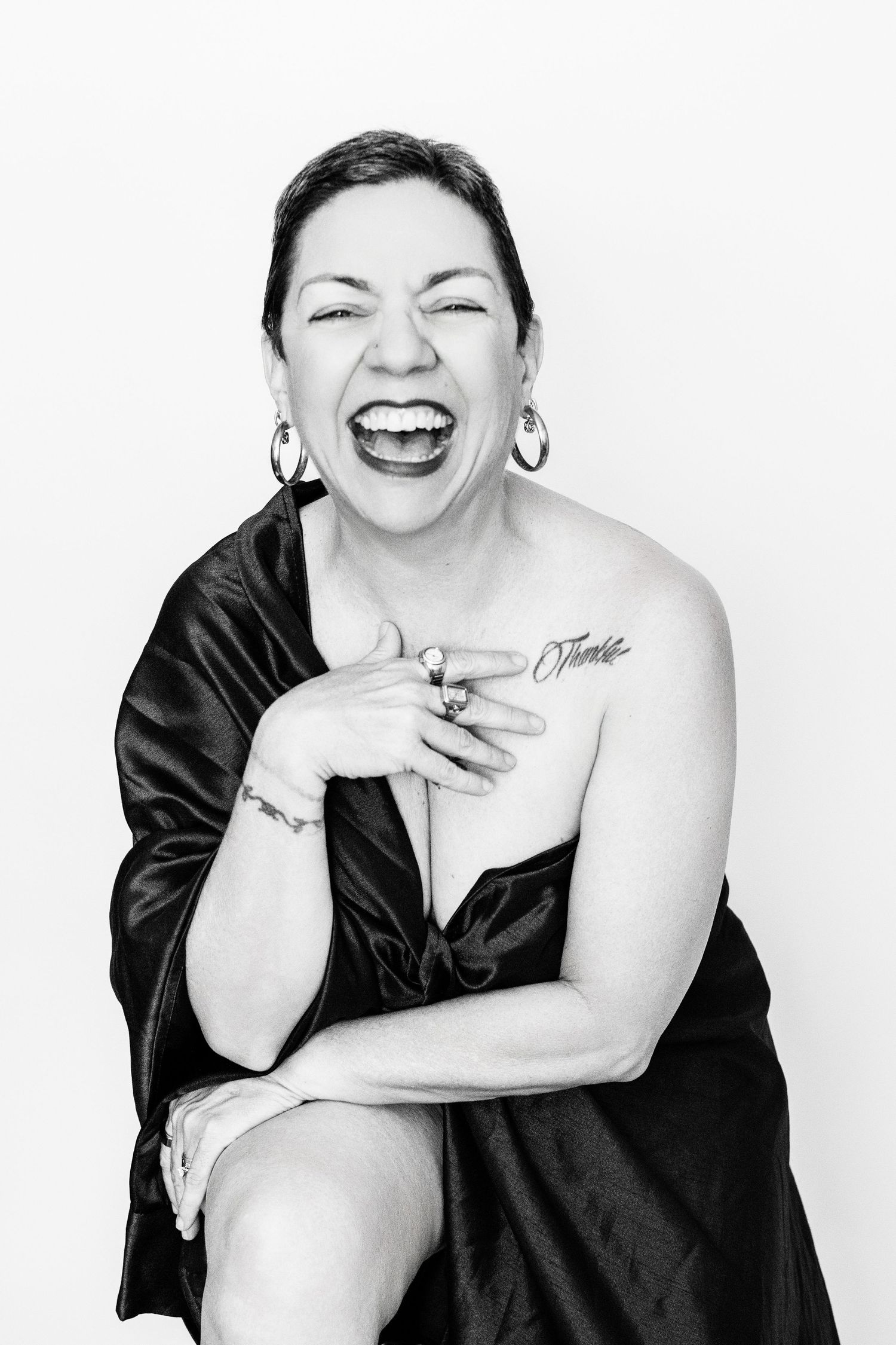 Joyful black and white portrait showing genuine laughter in a black off-shoulder dress.