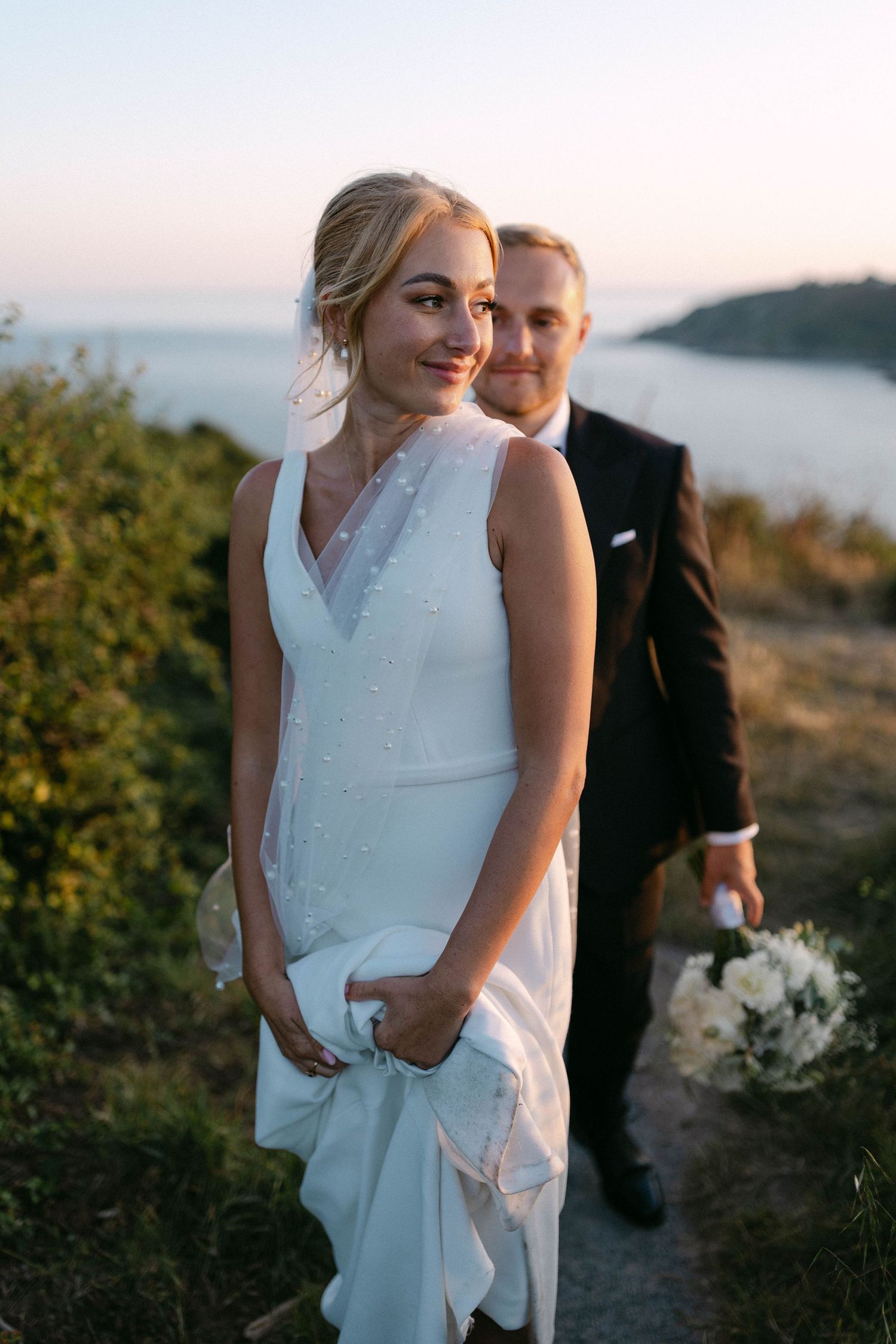 A sunset wedding portrait captured on a coastal hillside overlooking the ocean.