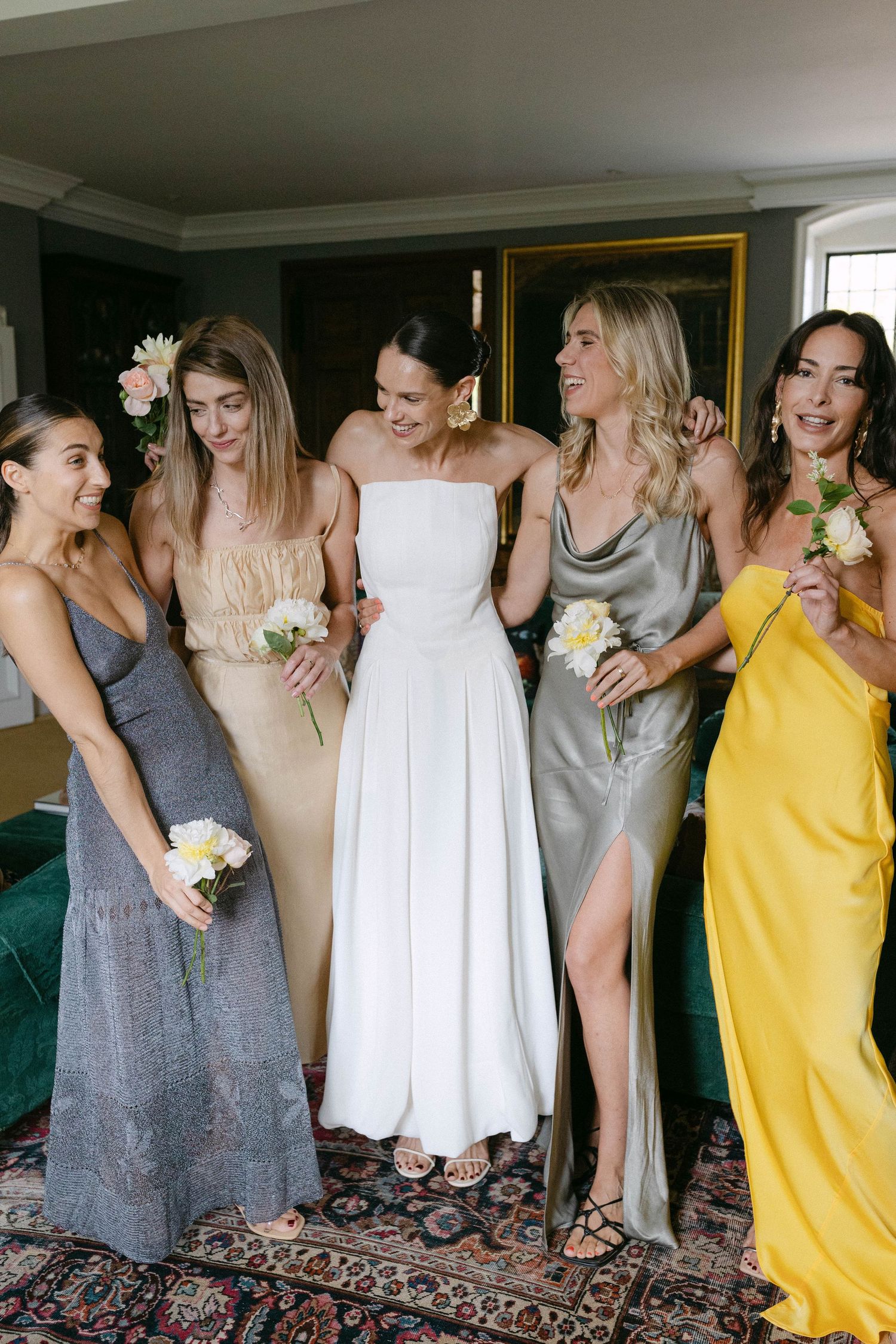 Bridesmaids in yellow and gray dresses gather for a candid group photo.