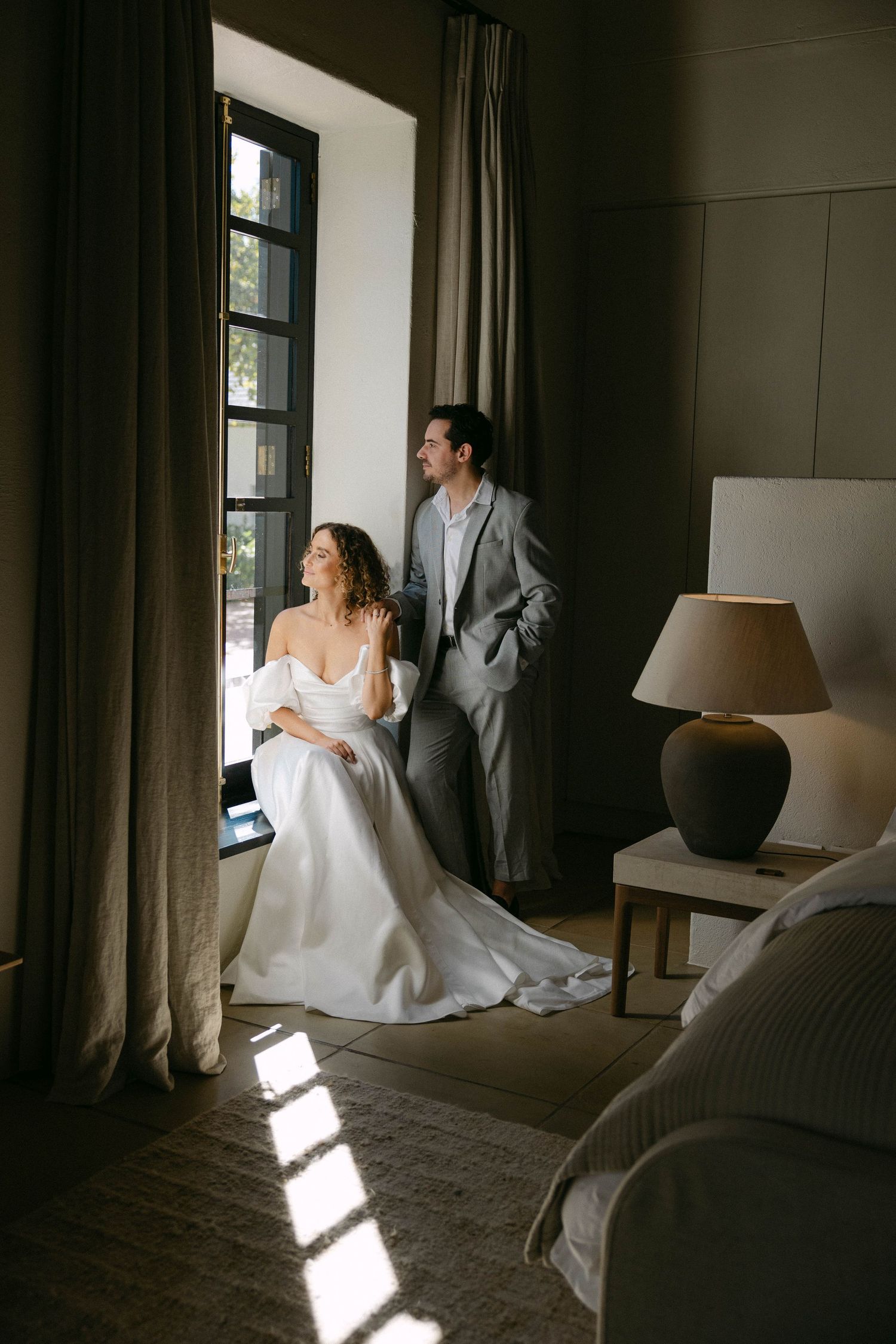 Sunlight streams through windows creating dramatic shadows in bridal preparation room.