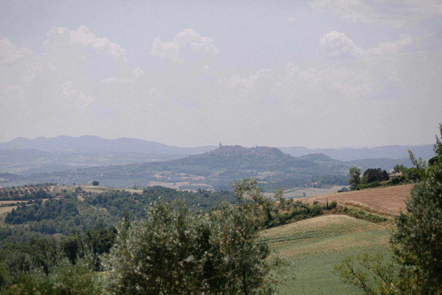 Rolling hills and mountains stretch into the distance under a soft blue sky with scattered clouds.