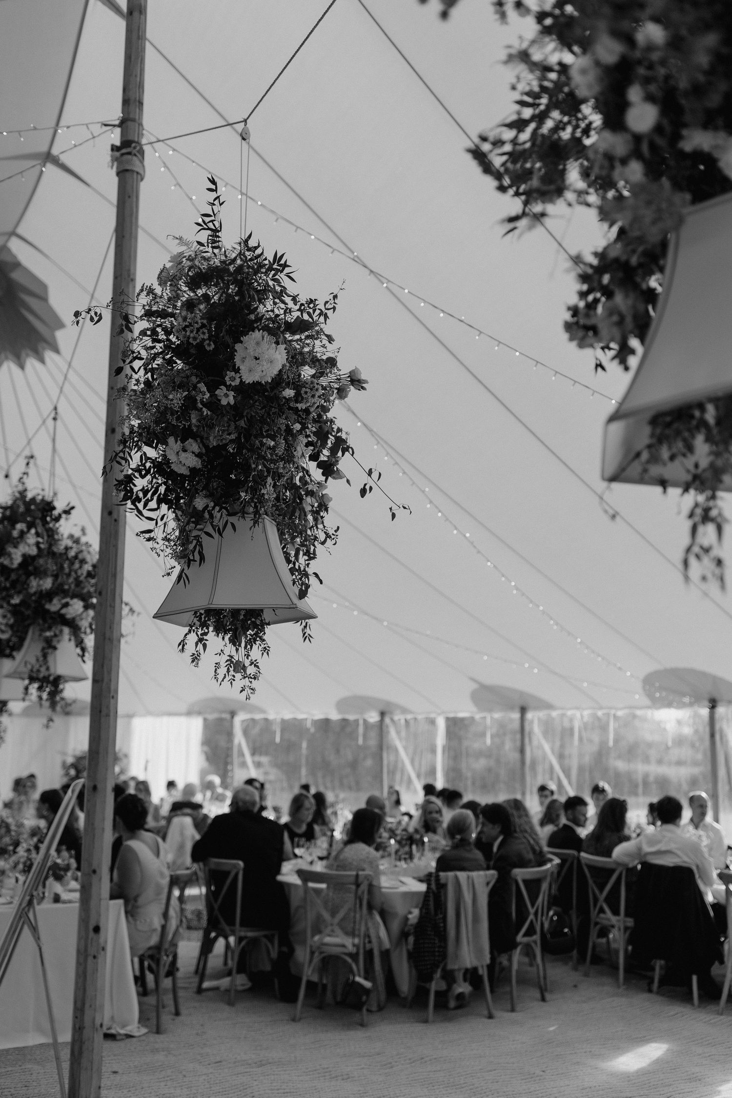 Large white wedding tent set up outdoors with guests seated at tables inside.