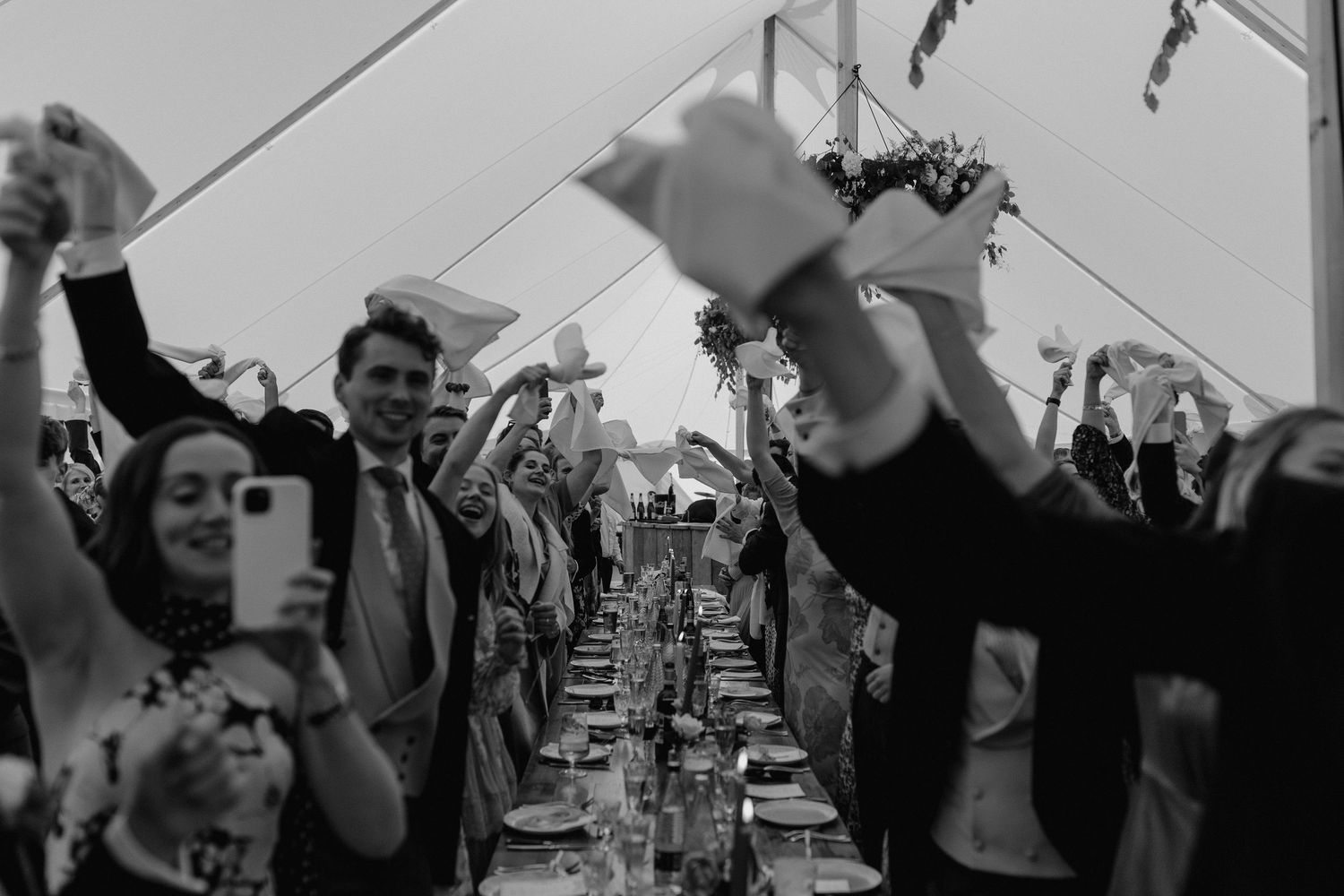 Black and white photo of wedding guests celebrating at a reception dinner.