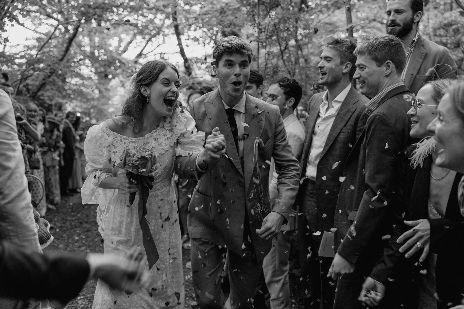Wedding guests shower the newlyweds with confetti during an outdoor celebration.
