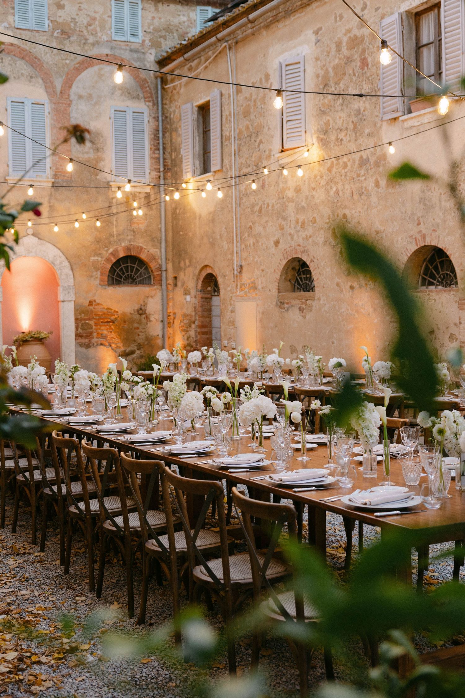 An elegant outdoor reception venue with string lights and rustic table settings. Tuscany Wedding