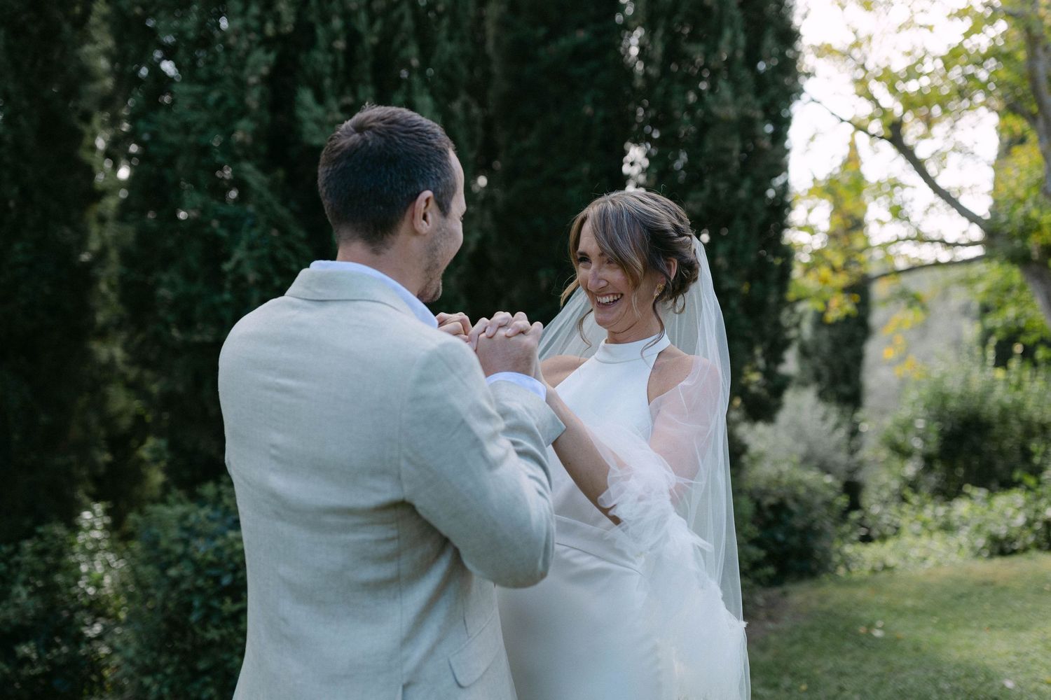 A joyful wedding dance moment captured in an outdoor garden setting.