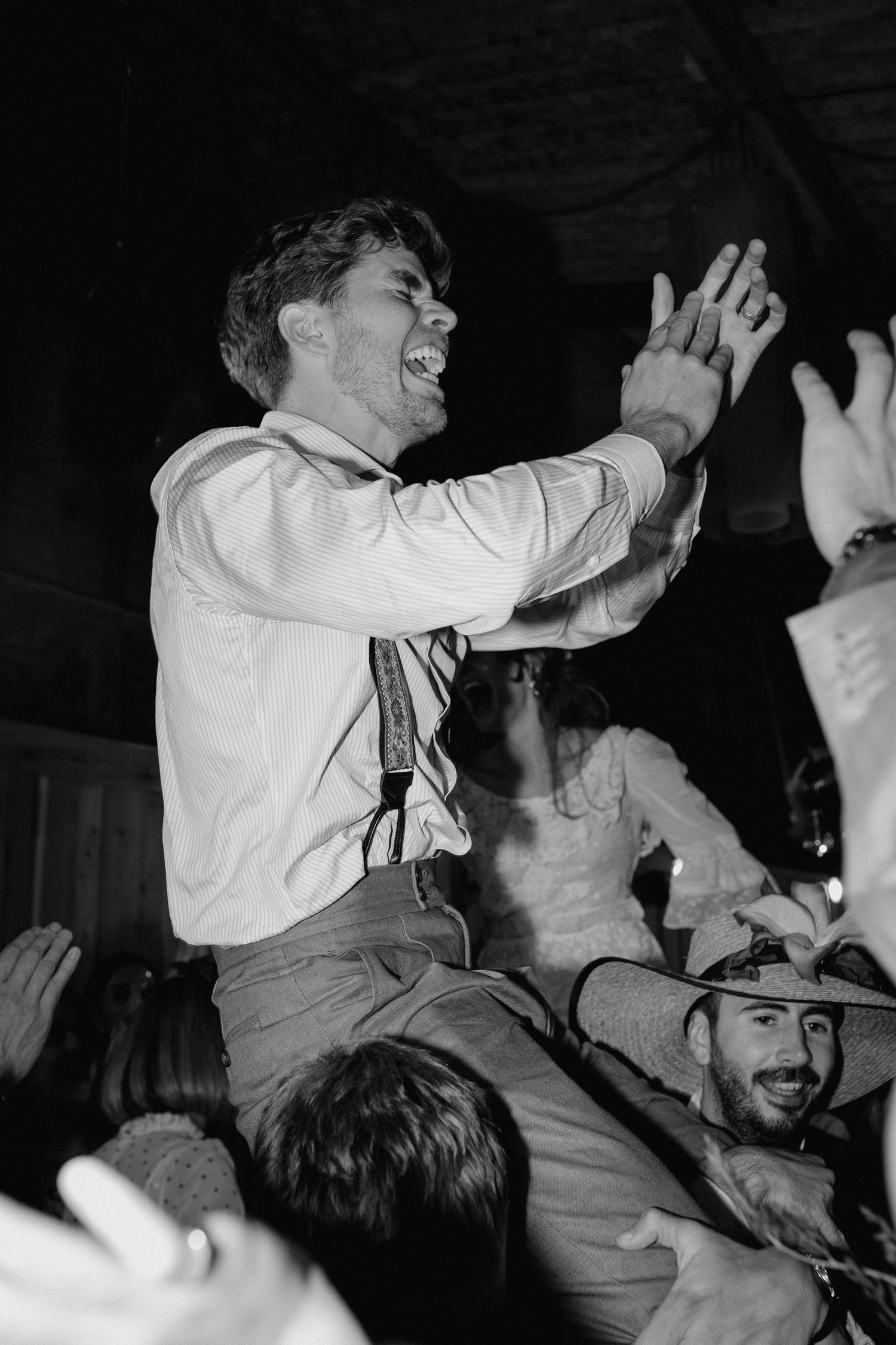 A celebratory moment captured in black and white as someone is lifted up during a lively reception.