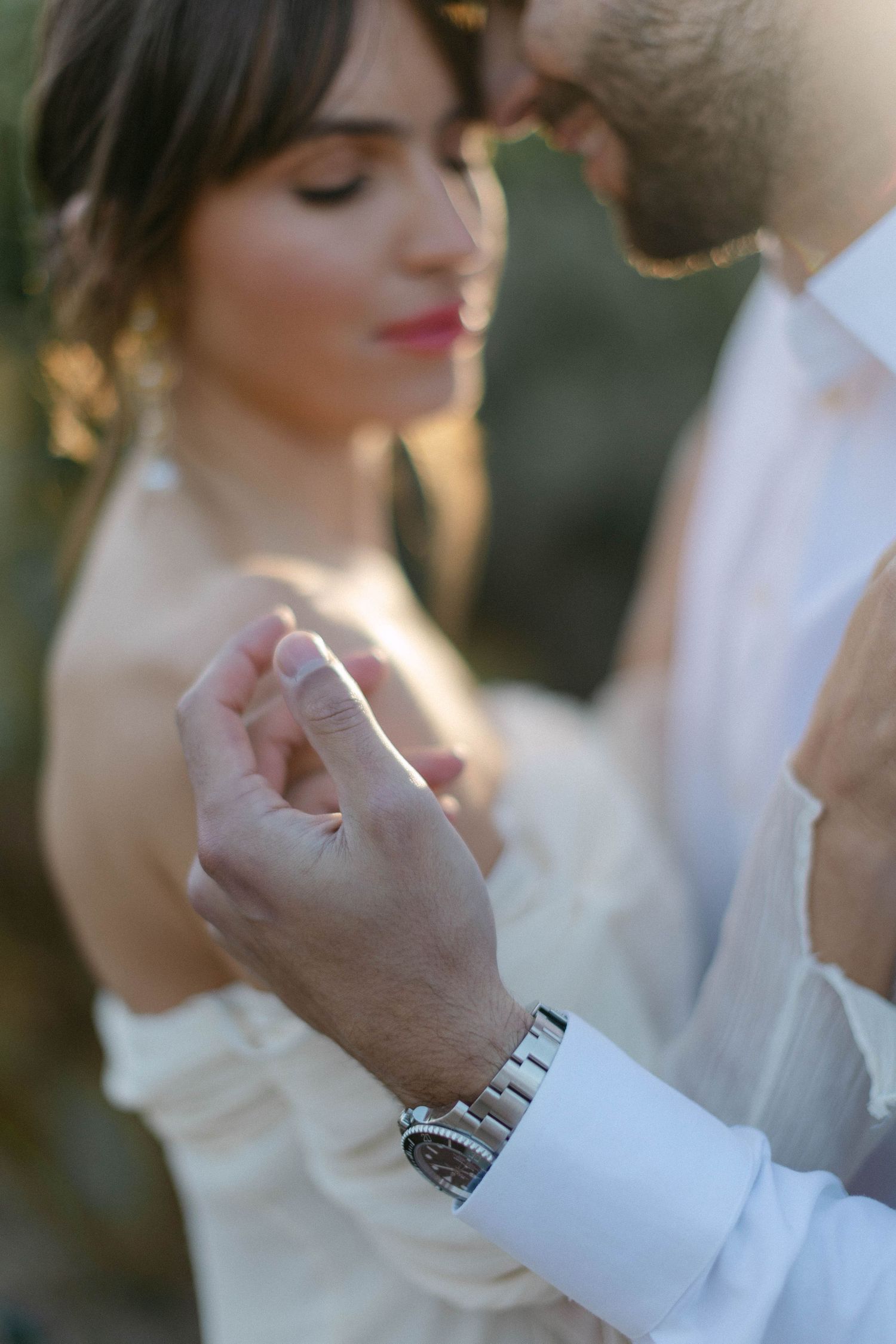 A romantic close-up of wedding rings being exchanged in warm sunlight.