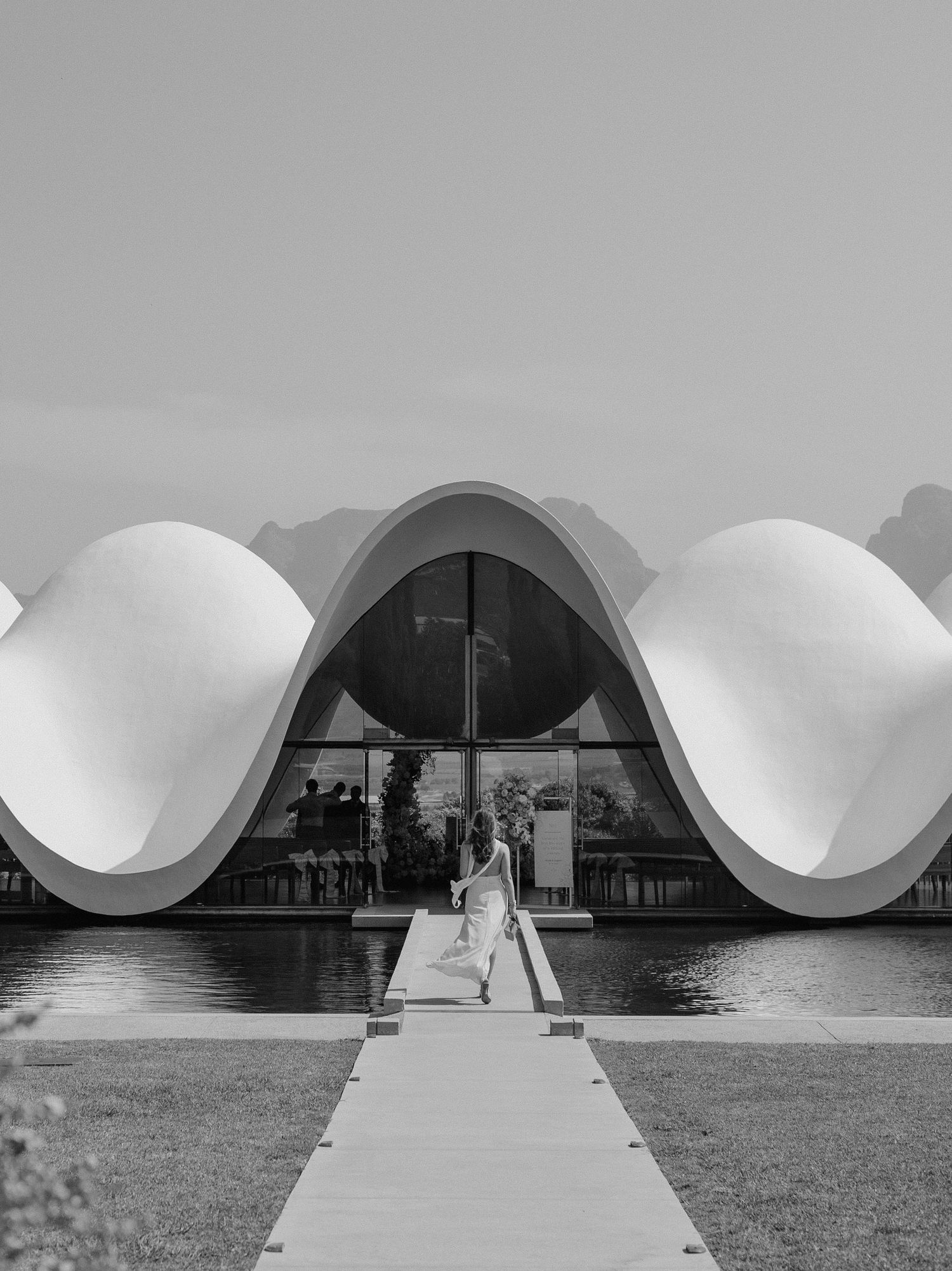 Modern architectural structure with curved white roof and symmetrical walkway design.
