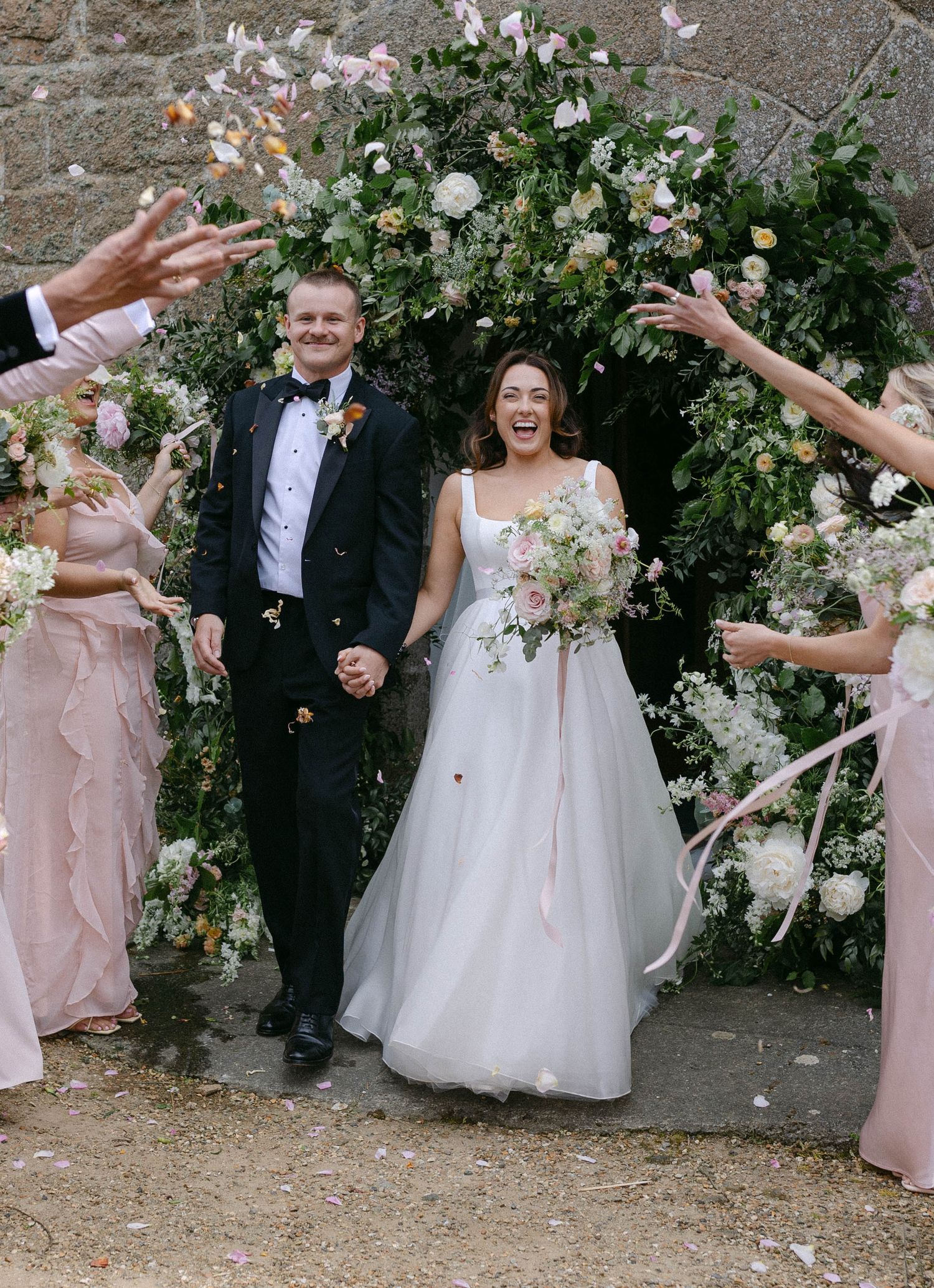 Wedding celebration under a floral arch with confetti being thrown. Guernsey.