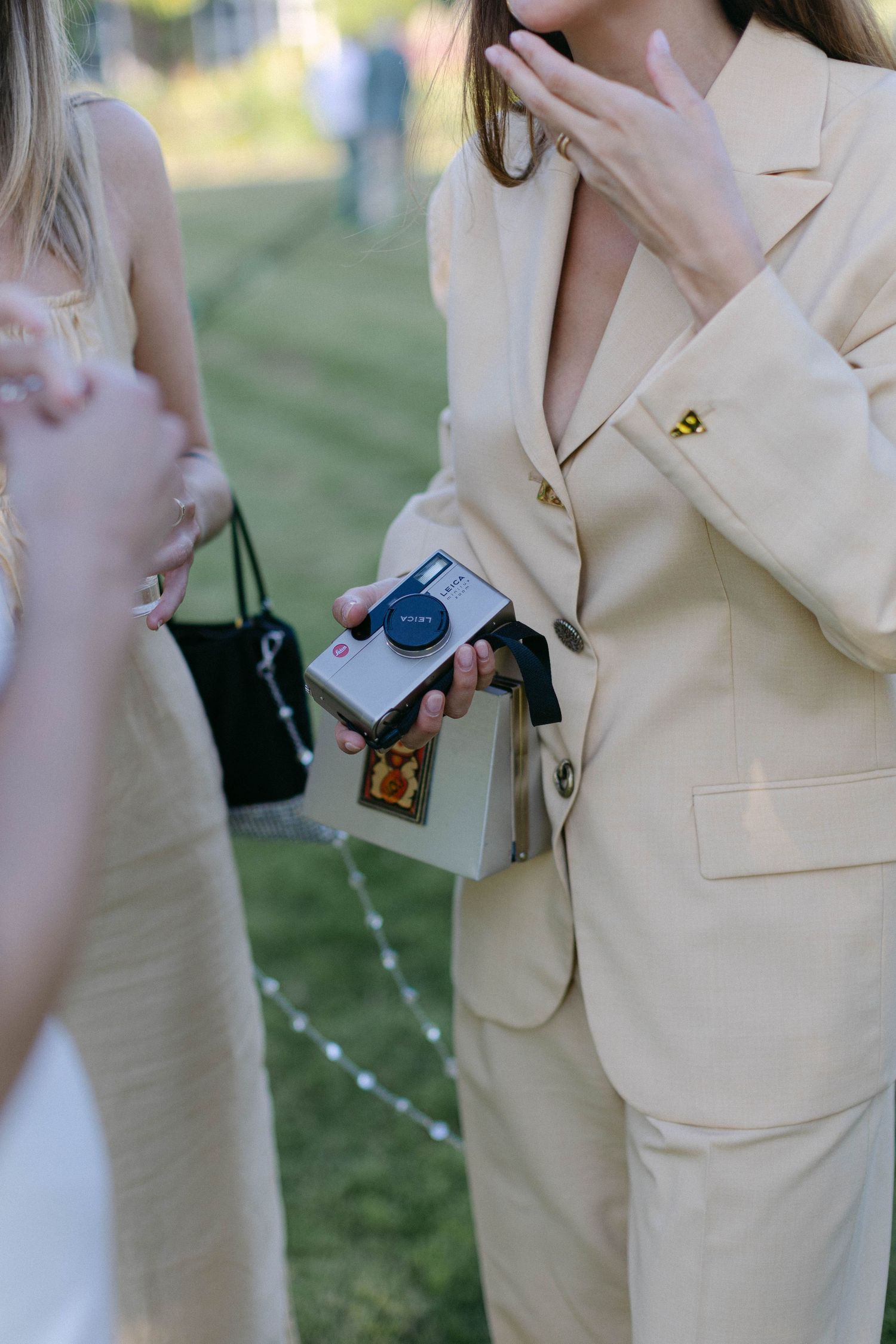 People wearing cream colored formal attire at an outdoor event.