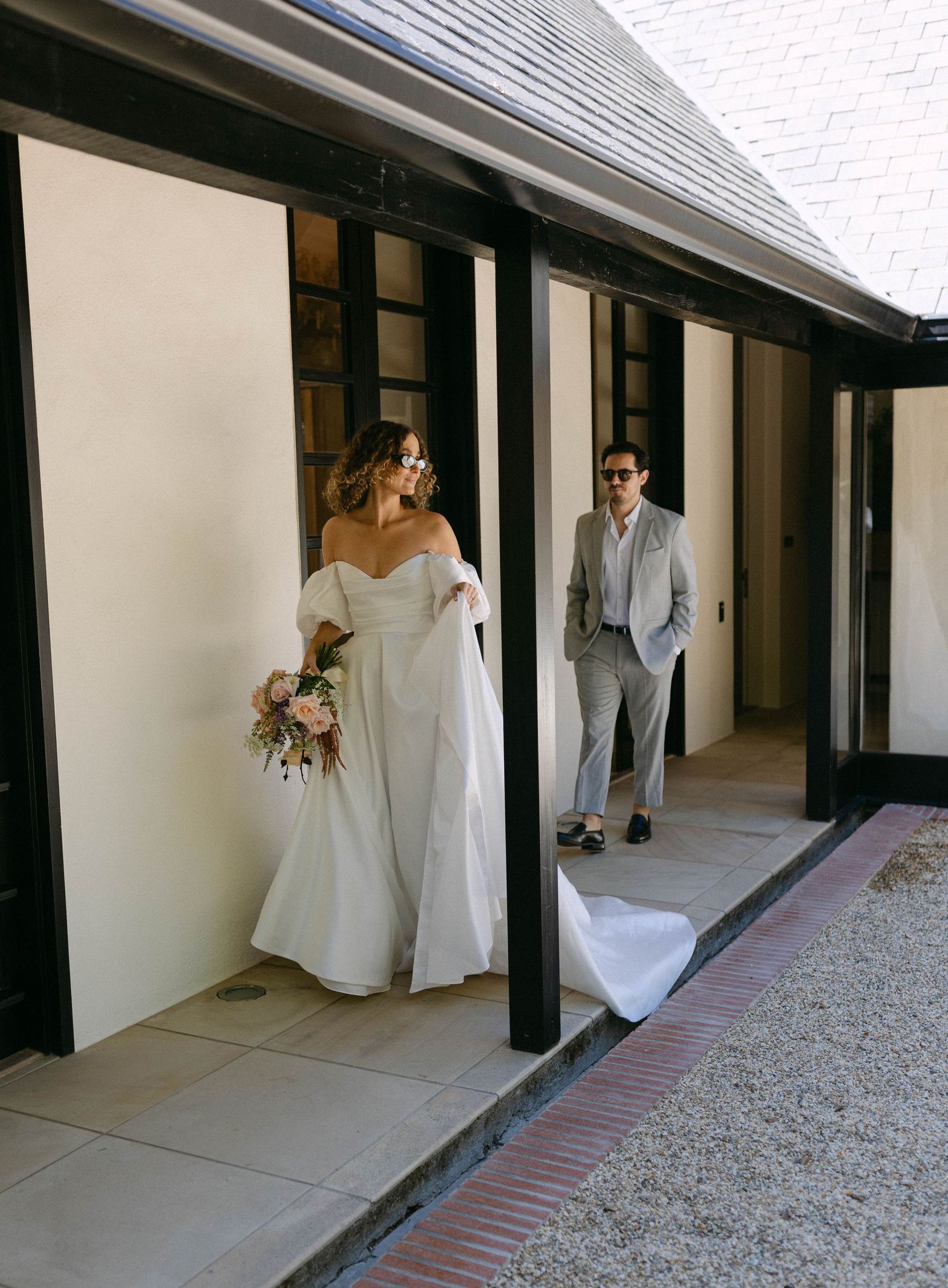 Elegant wedding scene in a white colonnade walkway with brick and concrete details.