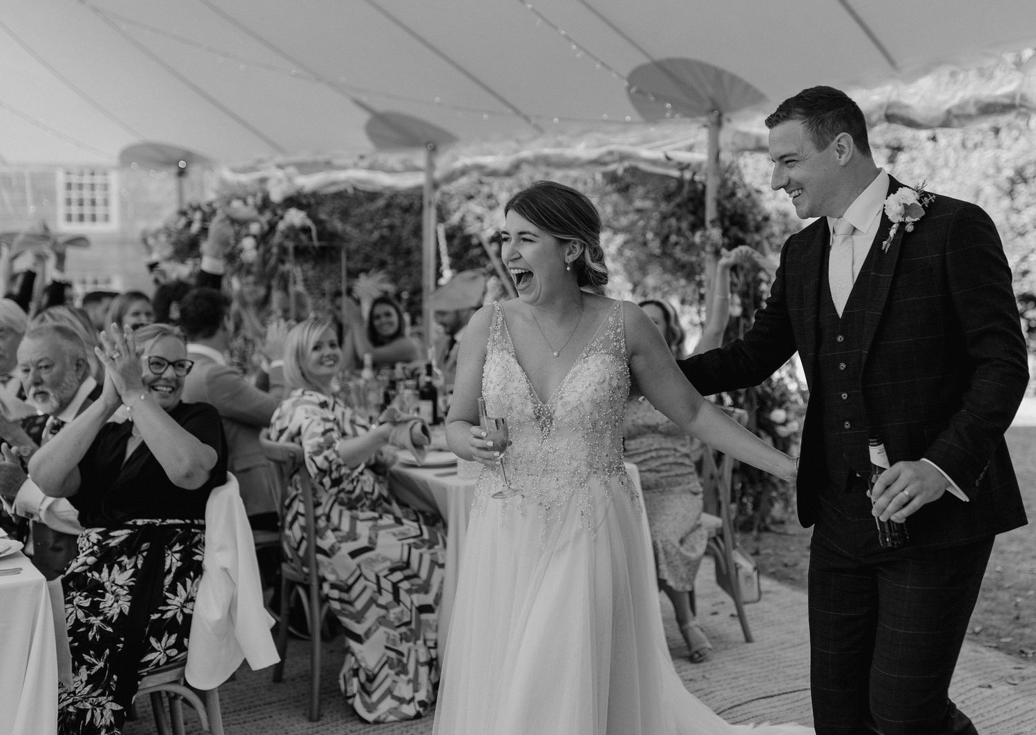 Wedding celebration under a white tent with guests enjoying the festivities.
