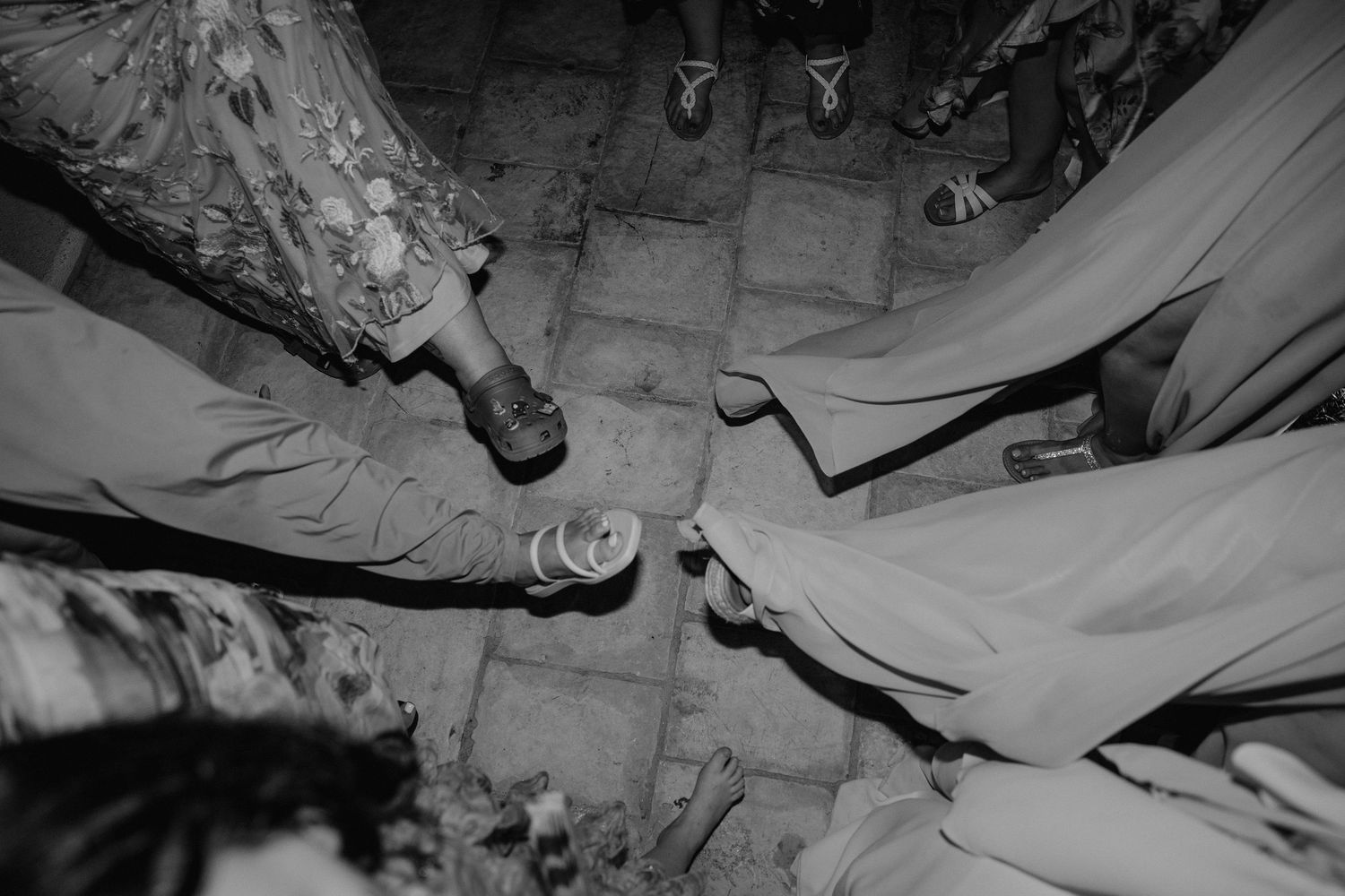 Black and white image of hands clinking champagne glasses together in celebration.