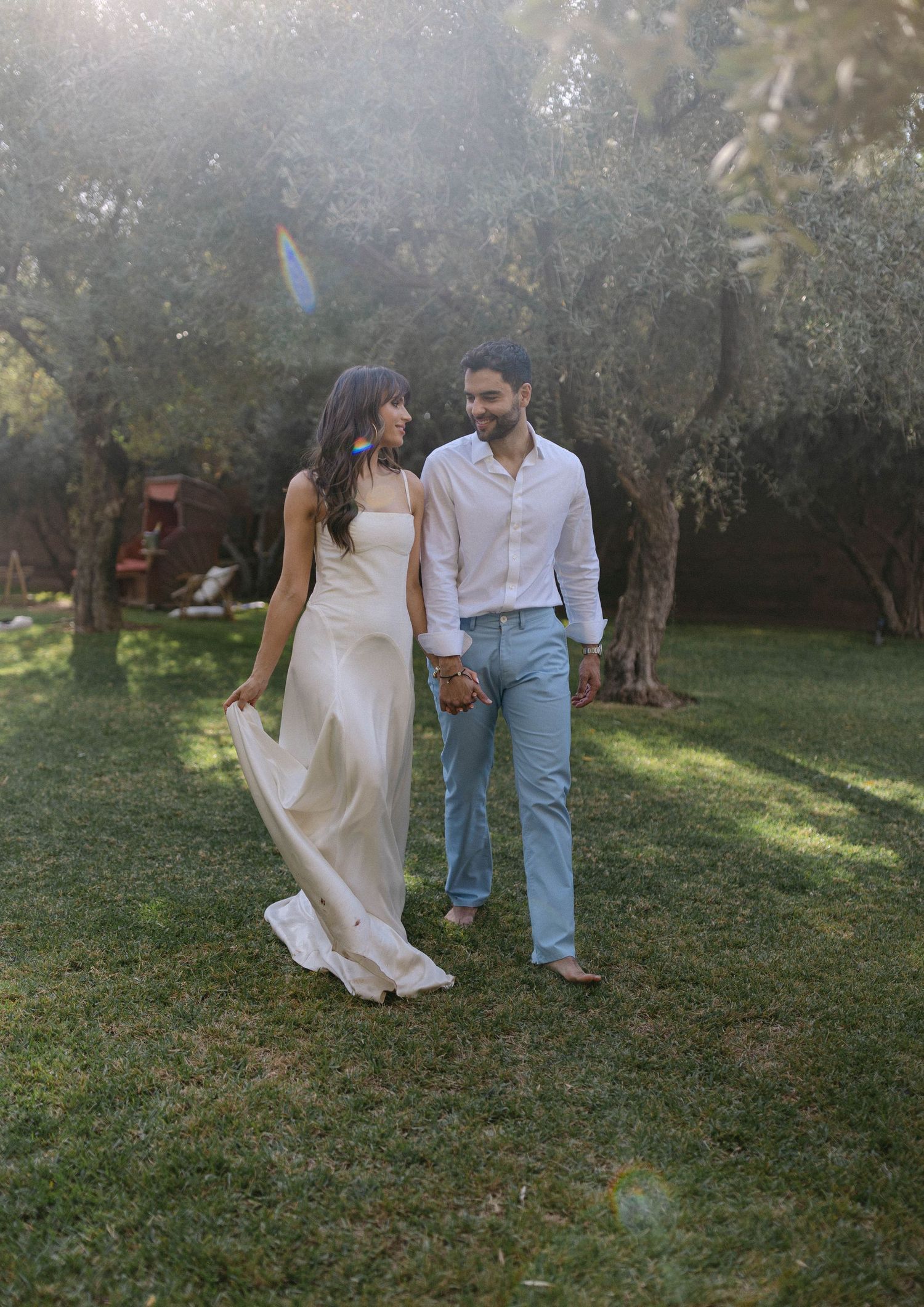 A couple walks through a garden setting in casual attire on a sunny day. Marrakech Wedding.