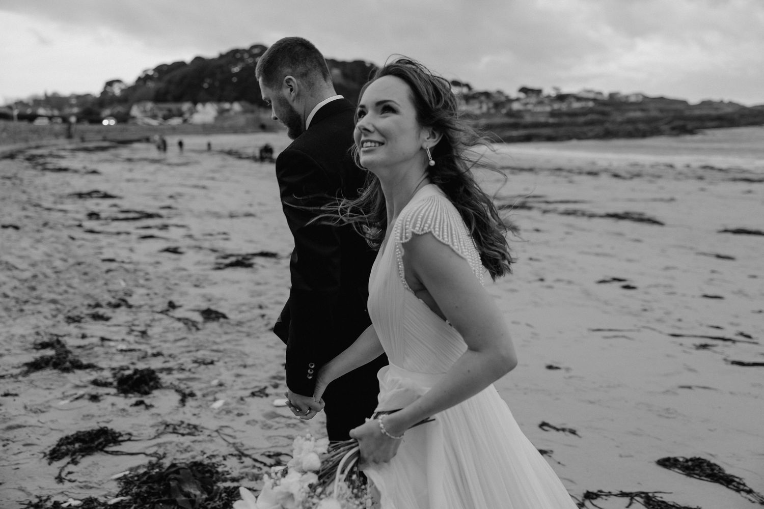 Joyful moment captured on beach with wedding couple in black and white photography.