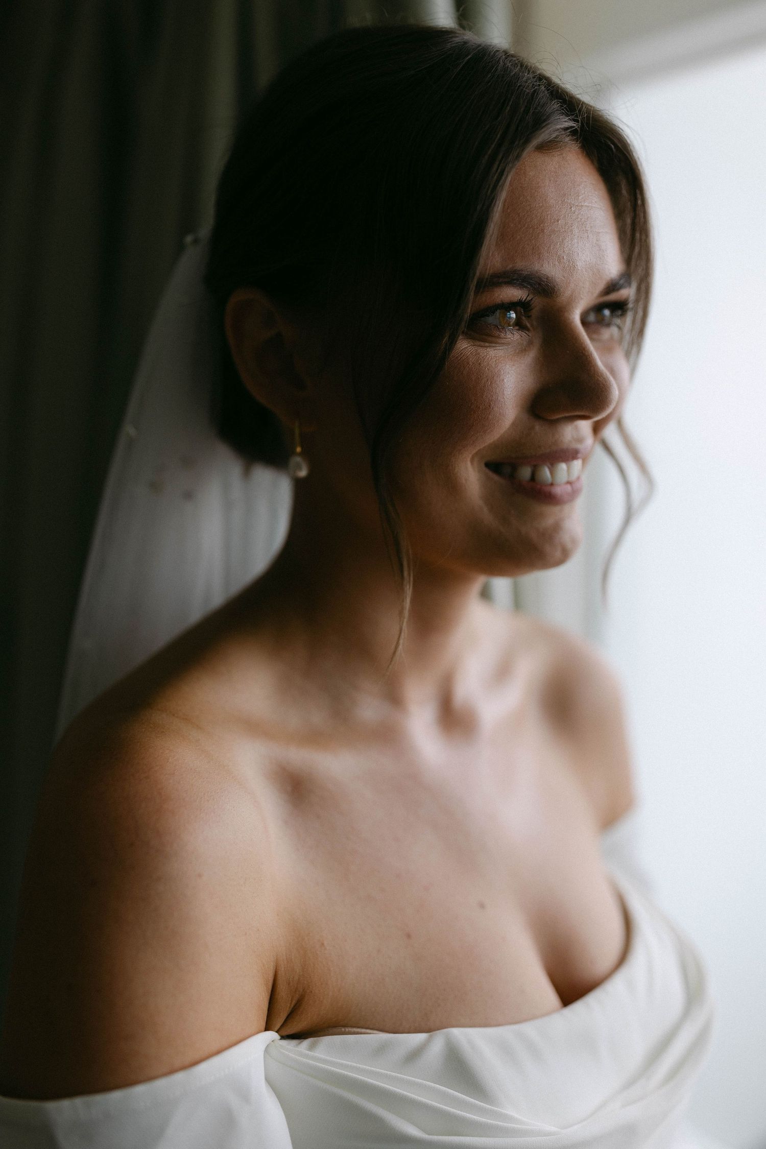 Elegant bridal portrait showing details of a white wedding dress in natural window light.