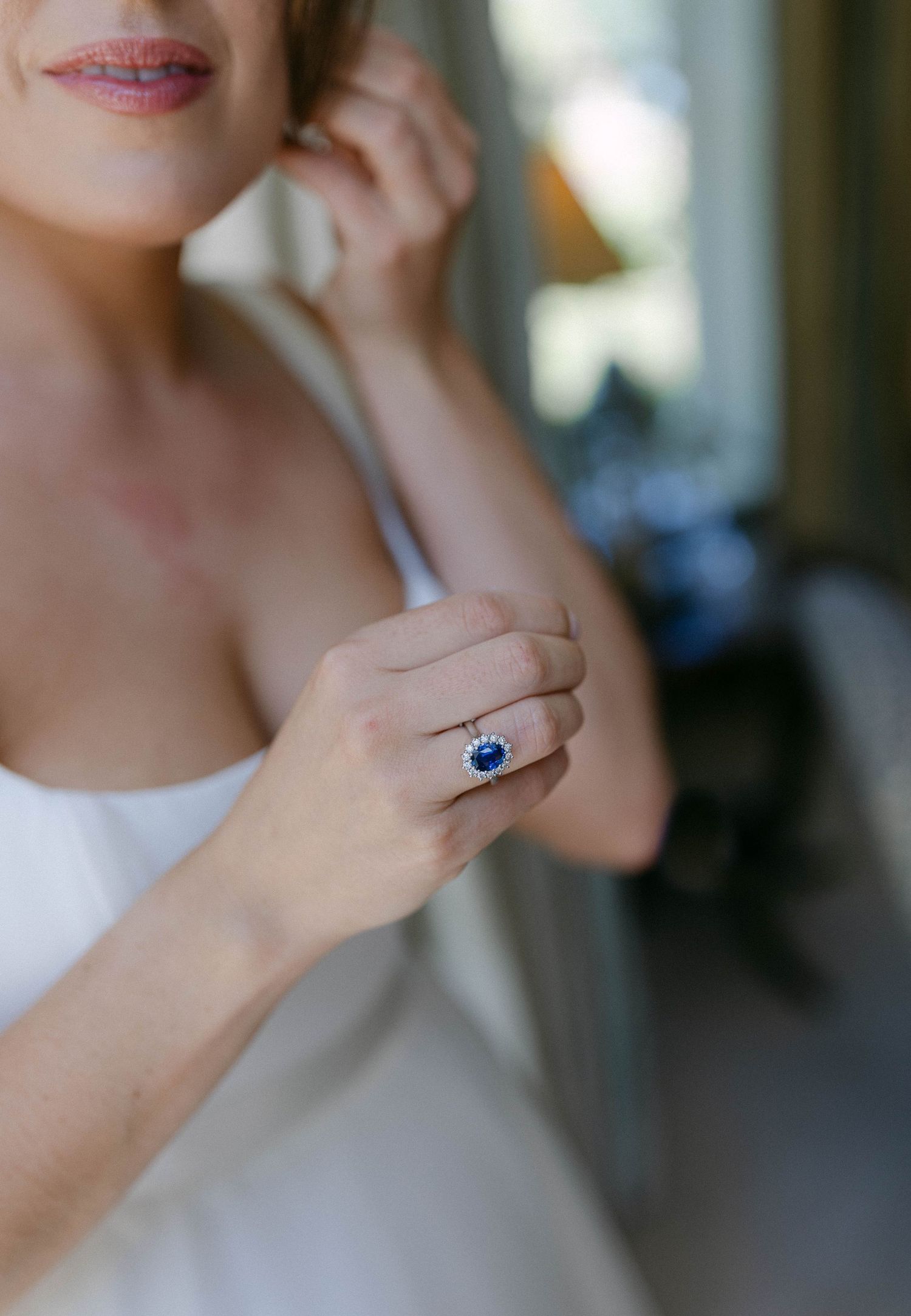 Close-up detail of a sapphire engagement ring on a hand.