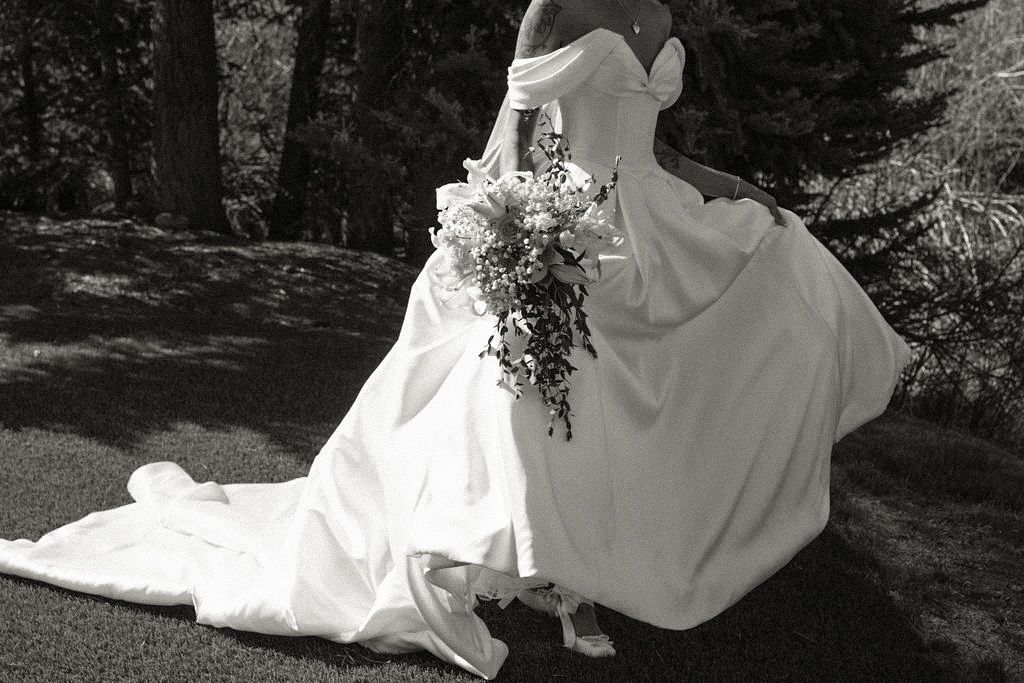 black and white wedding photo of a bride in a flowing ball gown holding a bouquet of flowers, taken in a forest setting - Colorado wedding