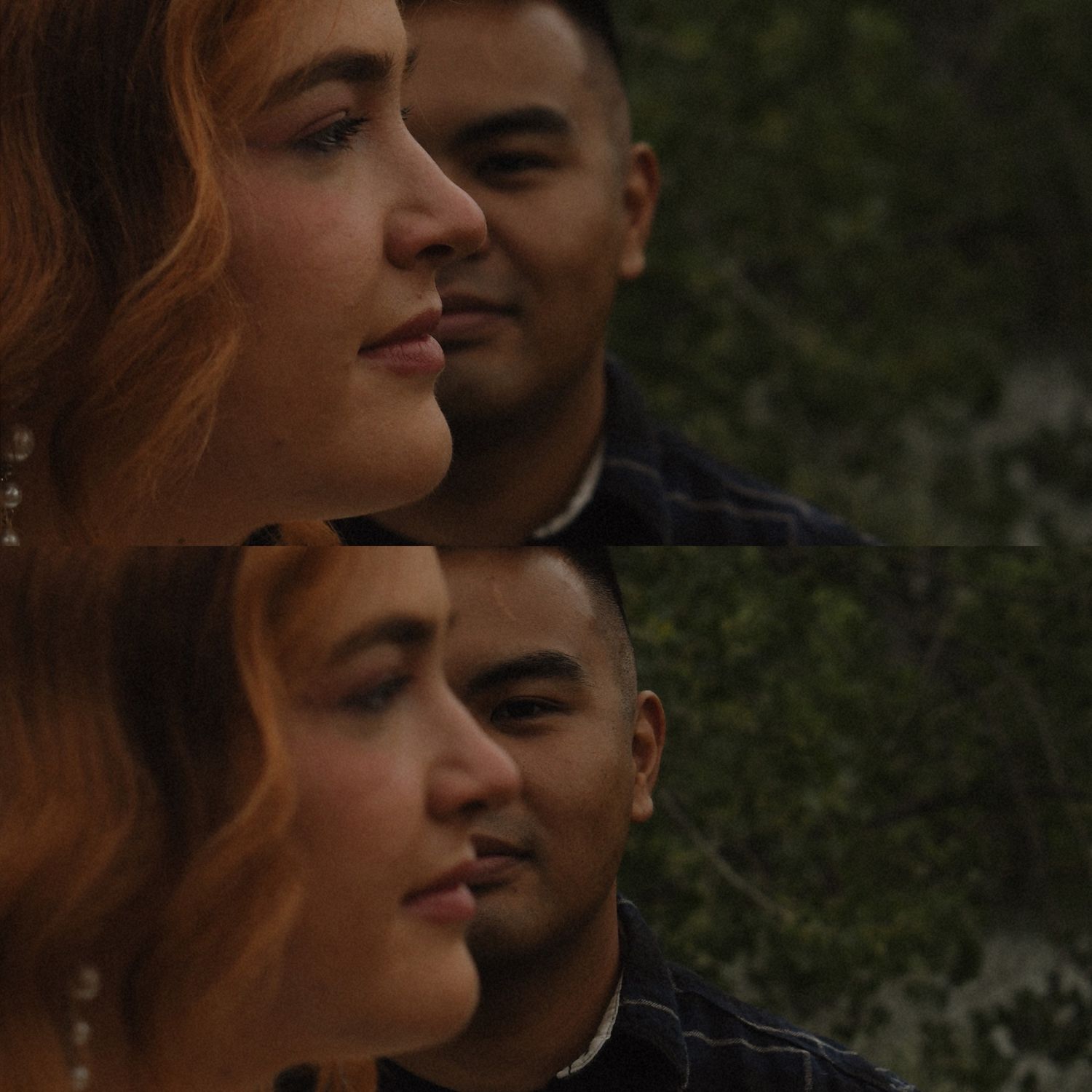 A young woman with red hair and a man stand close together outdoors, gazing into the distance near green foliage.