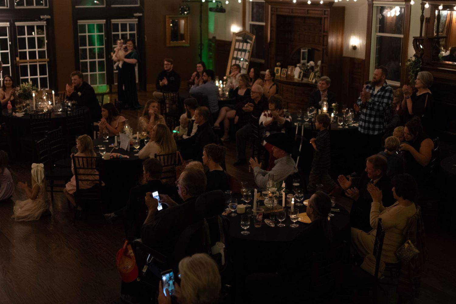Guests seated at candlelit tables during an elegant evening banquet event in a dimly lit venue.