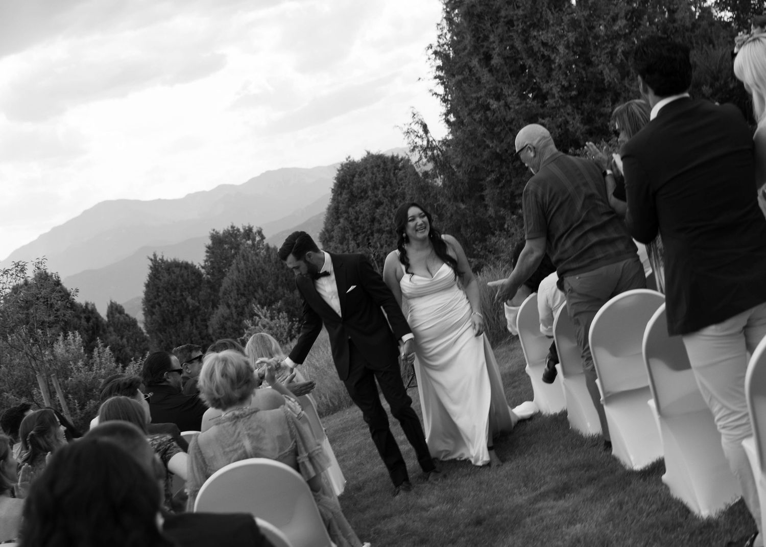 bride and groom coming back down the aisle and being celebrated by friends and family after mountain ceremony, black and white image