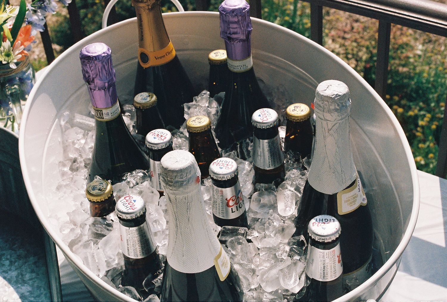 A large silver bucket filled with ice and assorted champagne and wine bottles chilling for a celebration.