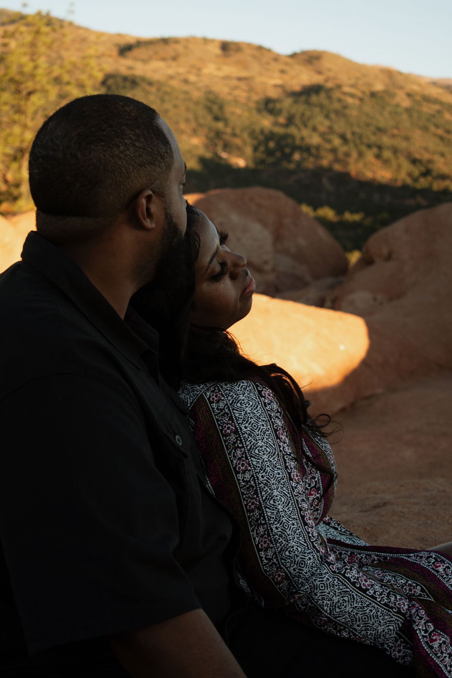 couple in the mountains on red rocks sitting snuggled together