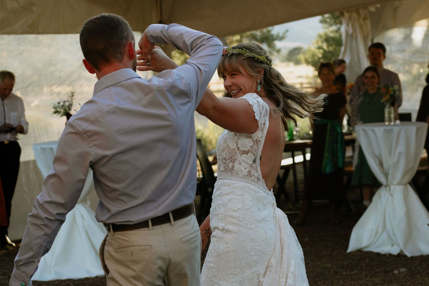 Bride and groom share their first dance under a tent at an outdoor wedding reception.