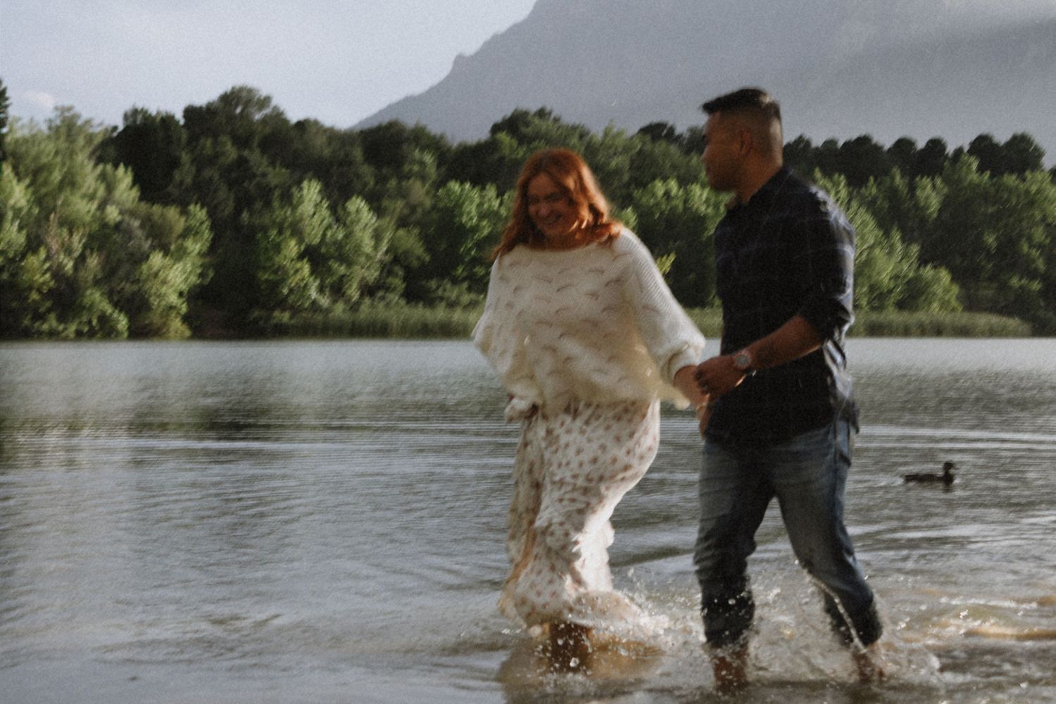 couple running through water together, mountain lake engagement session, ducks