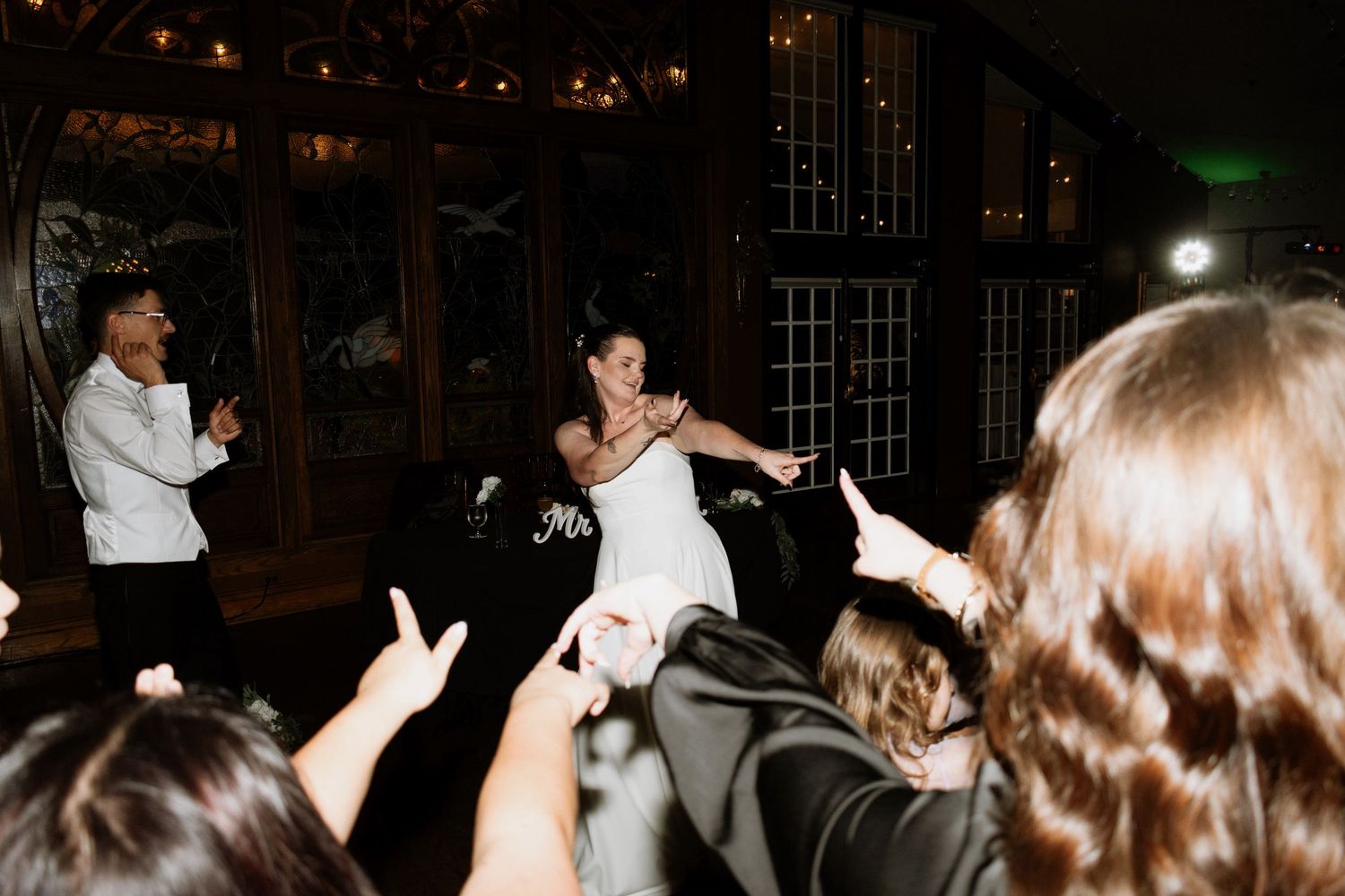 Bride and groom share a romantic dance surrounded by cheering guests at elegant wedding reception.