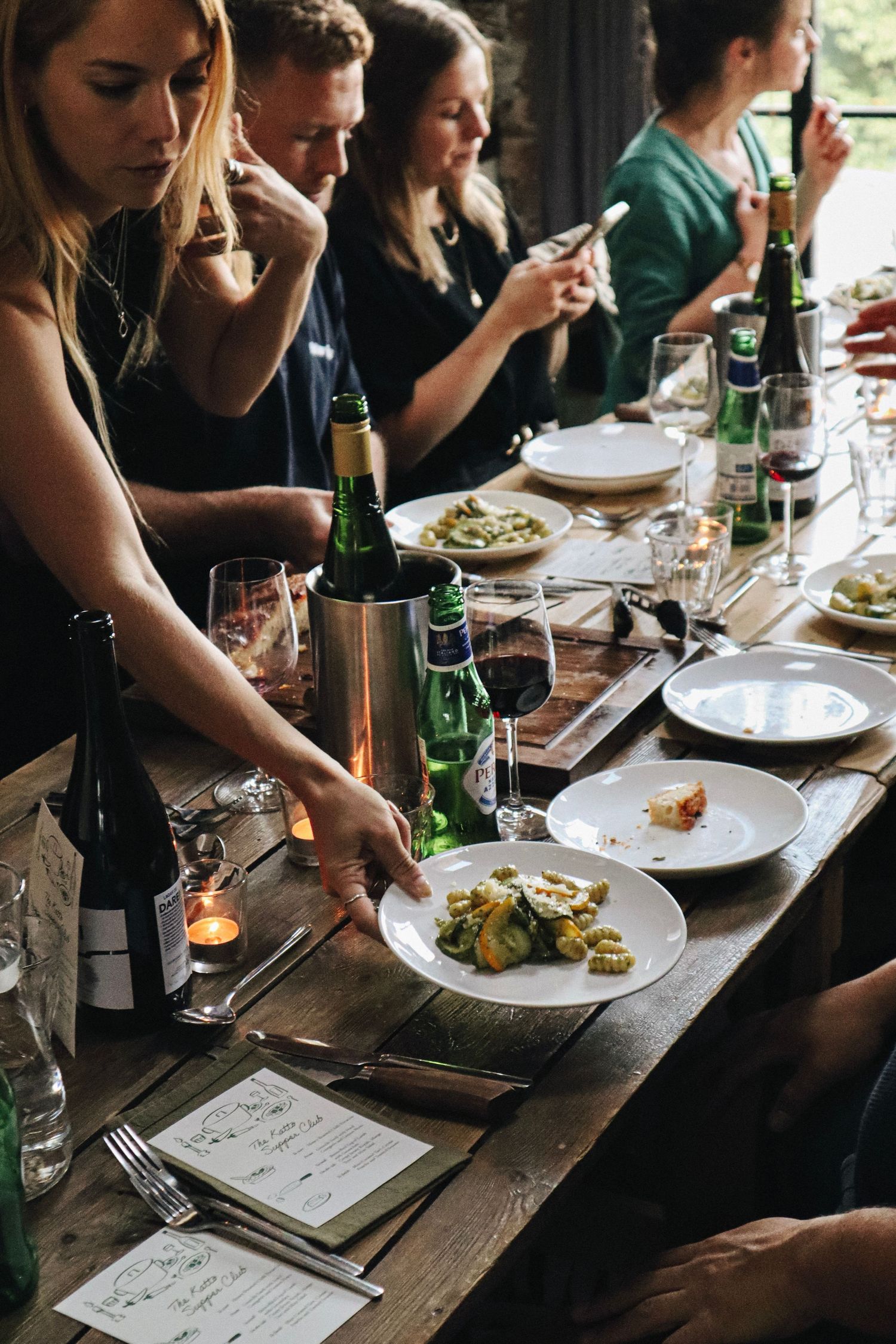 A woman lays down a plate of food at a dining event in The Forge, Bristol