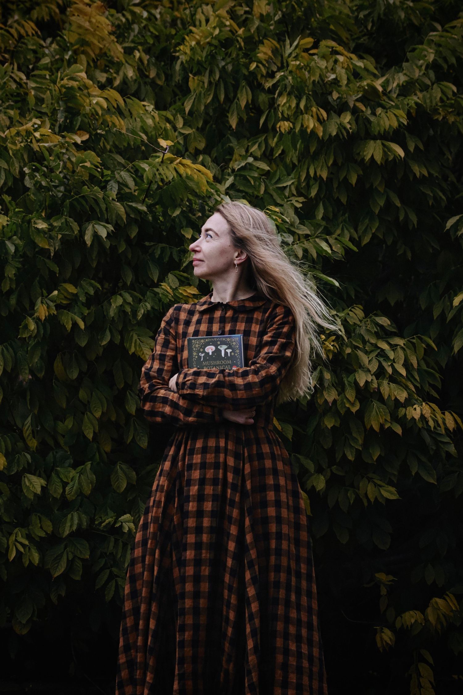 a portrait of a woman holding a book in an autumnal scene