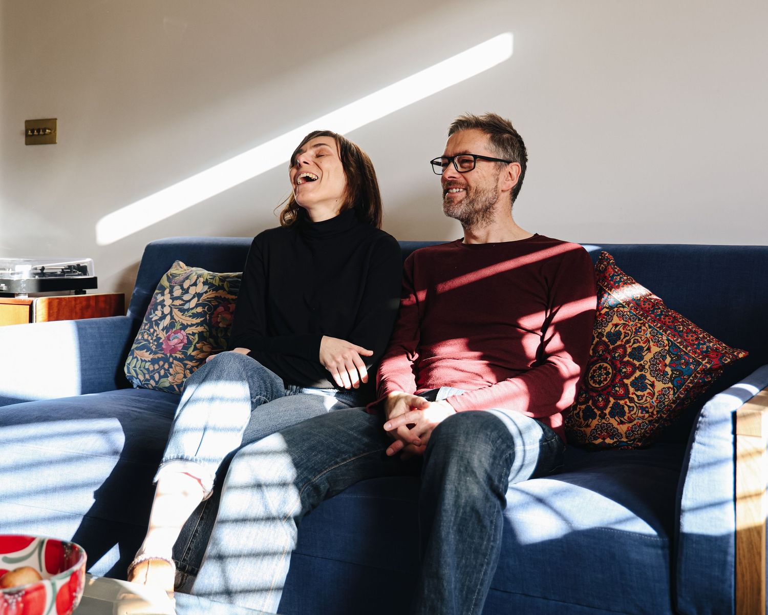 a couple sit comfortably on their sofa in their home