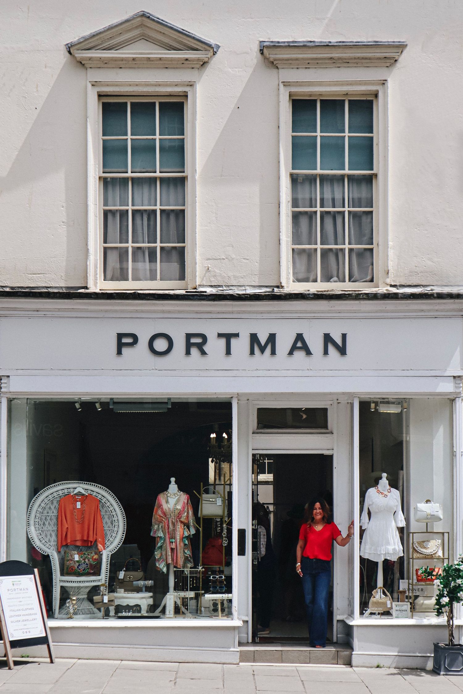 A storefront with the shop owner posing in the doorway