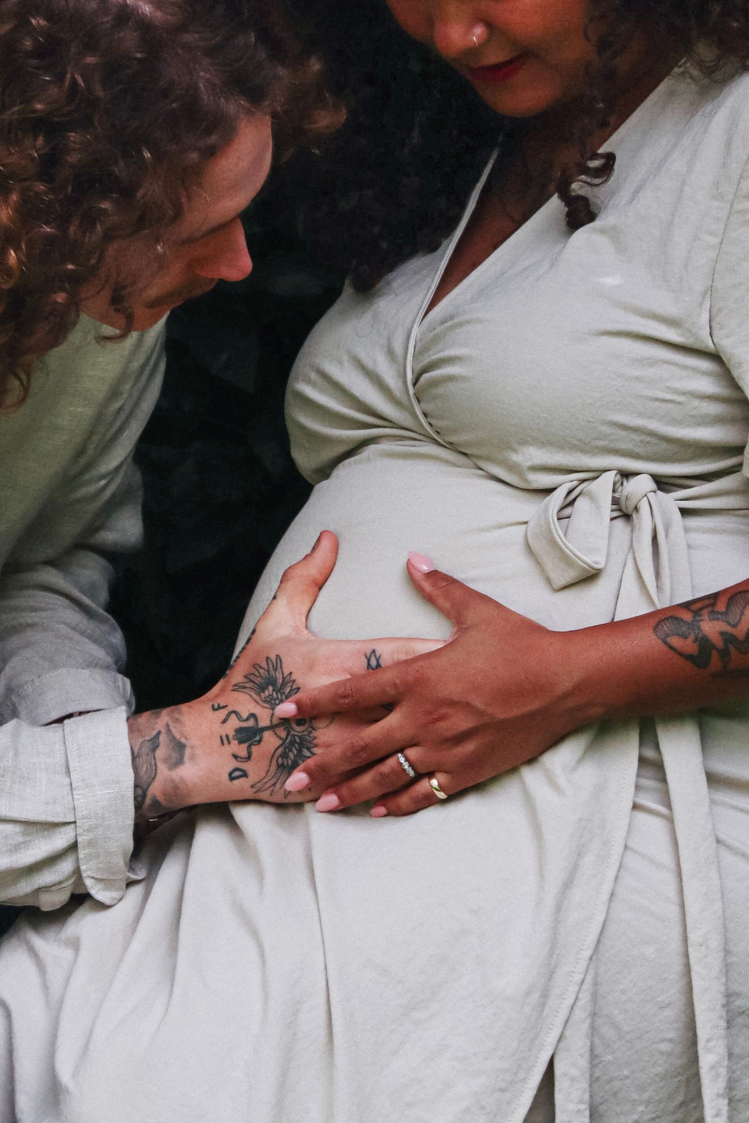 A man caresses the pregnant belly of his new wife on their wedding day