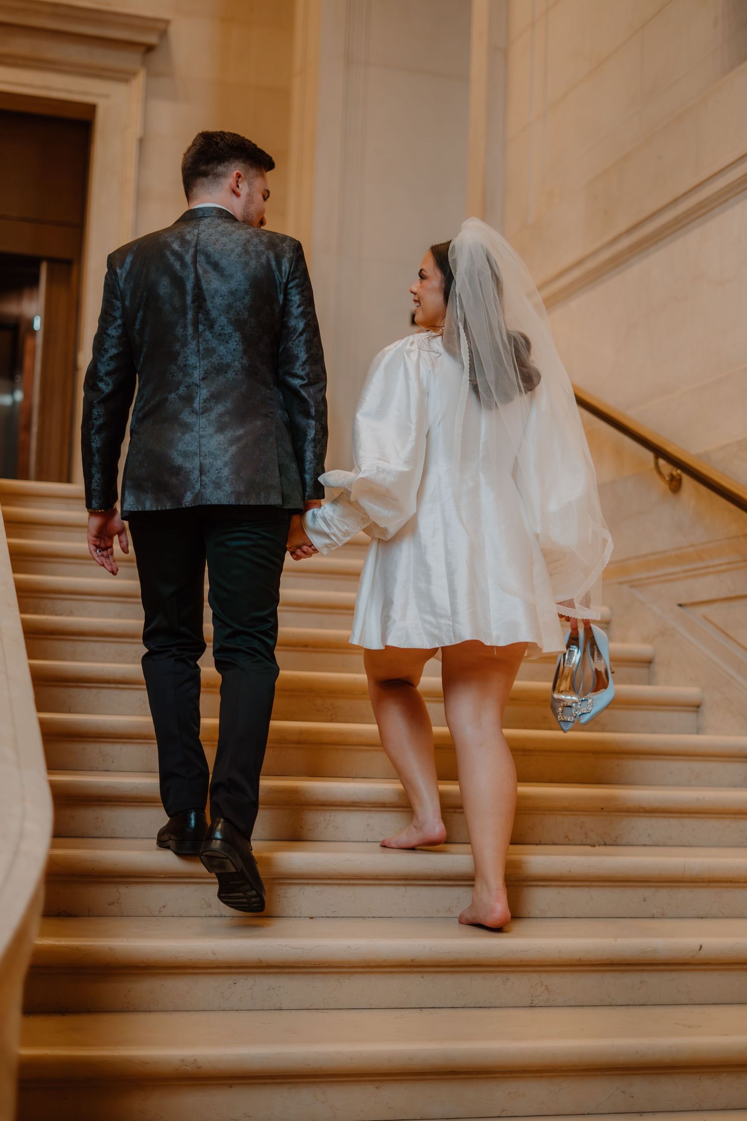 Bride and groom smiling at each other as they are walking up the stairs at the National Gallery of Art in Washington DC