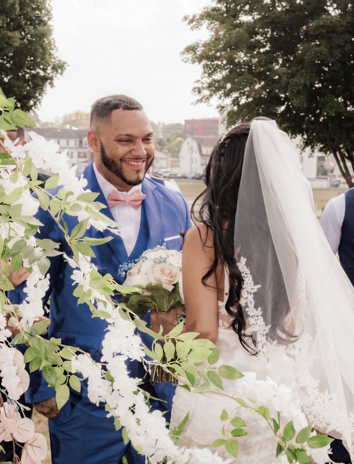 Wedding couple shares joyful moment surrounded by white floral arrangements.